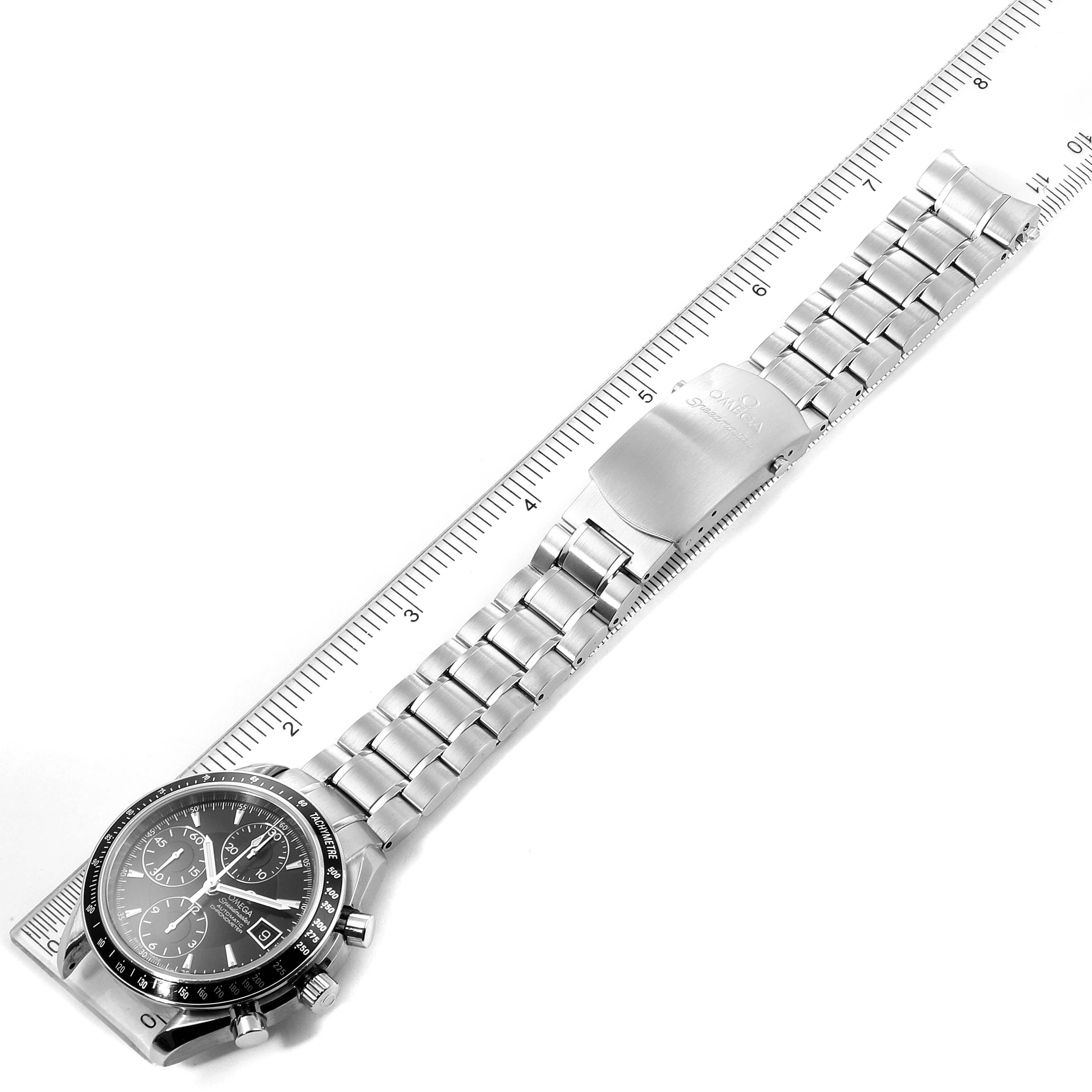 The image shows an Omega Speedmaster 3210.50.00 Men's Stainless Steel Black Dial 3210.50.00 Men's Stainless Steel Black Dial watch laid flat next to a ruler, displaying the watch face, bracelet, and clasp.