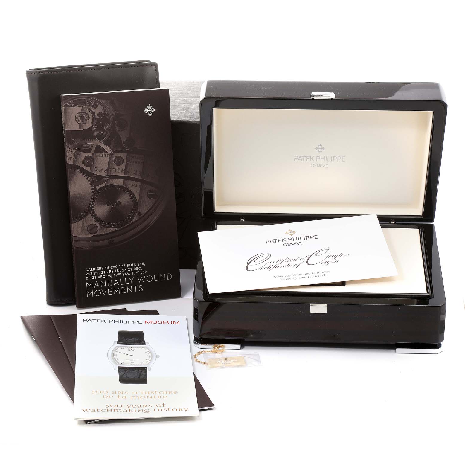 The image shows accessories for a Patek Philippe Calatrava 5119J Men's Yellow Gold White Dial 5119J Men's Yellow Gold White Dial watch, including its box, manuals, and a certificate.