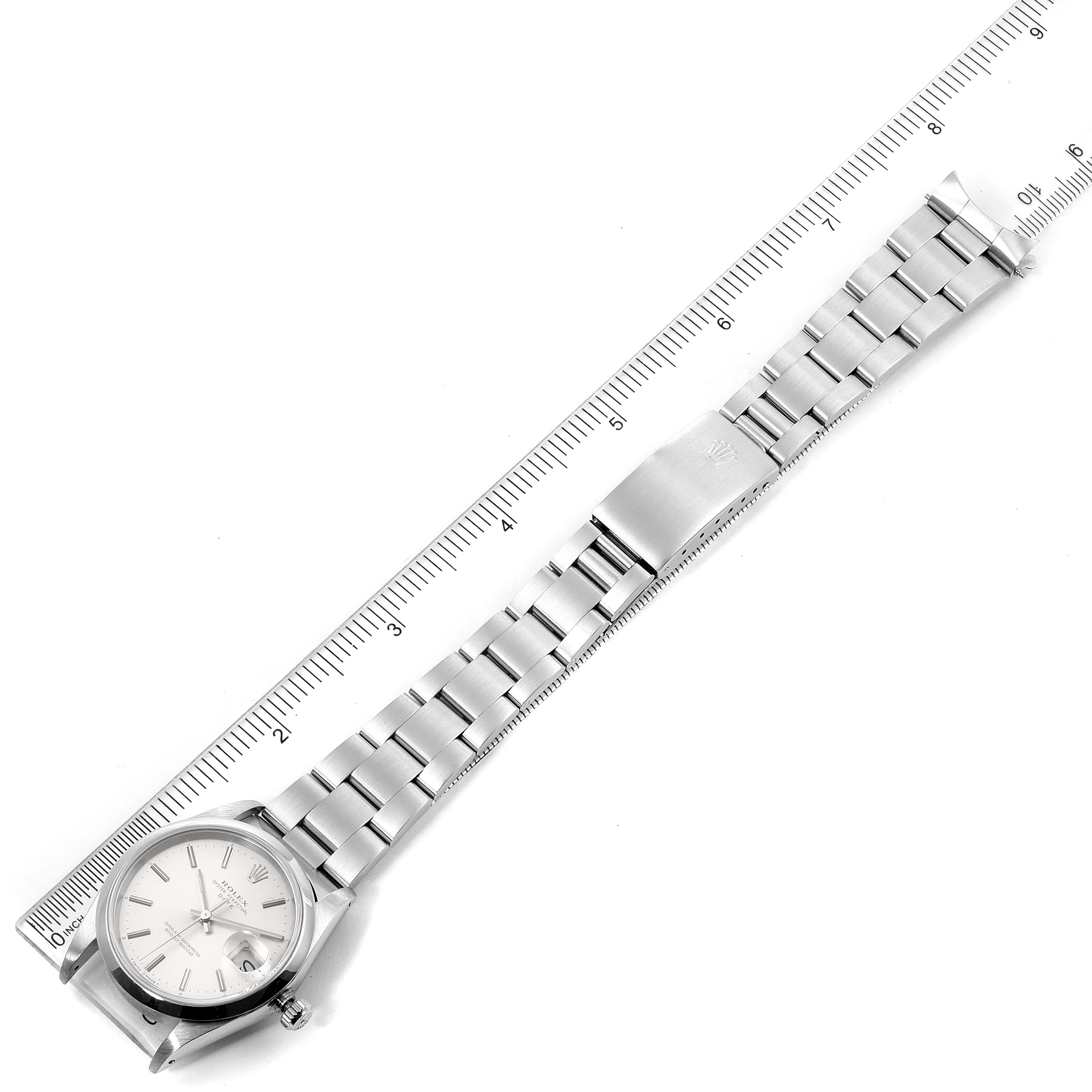 The Rolex Date 15200 Men's Stainless Steel Silver Dial 15200 Men's Stainless Steel Silver Dial model watch is shown from a top-down angle, displaying the full face, bracelet, and clasp next to a ruler.