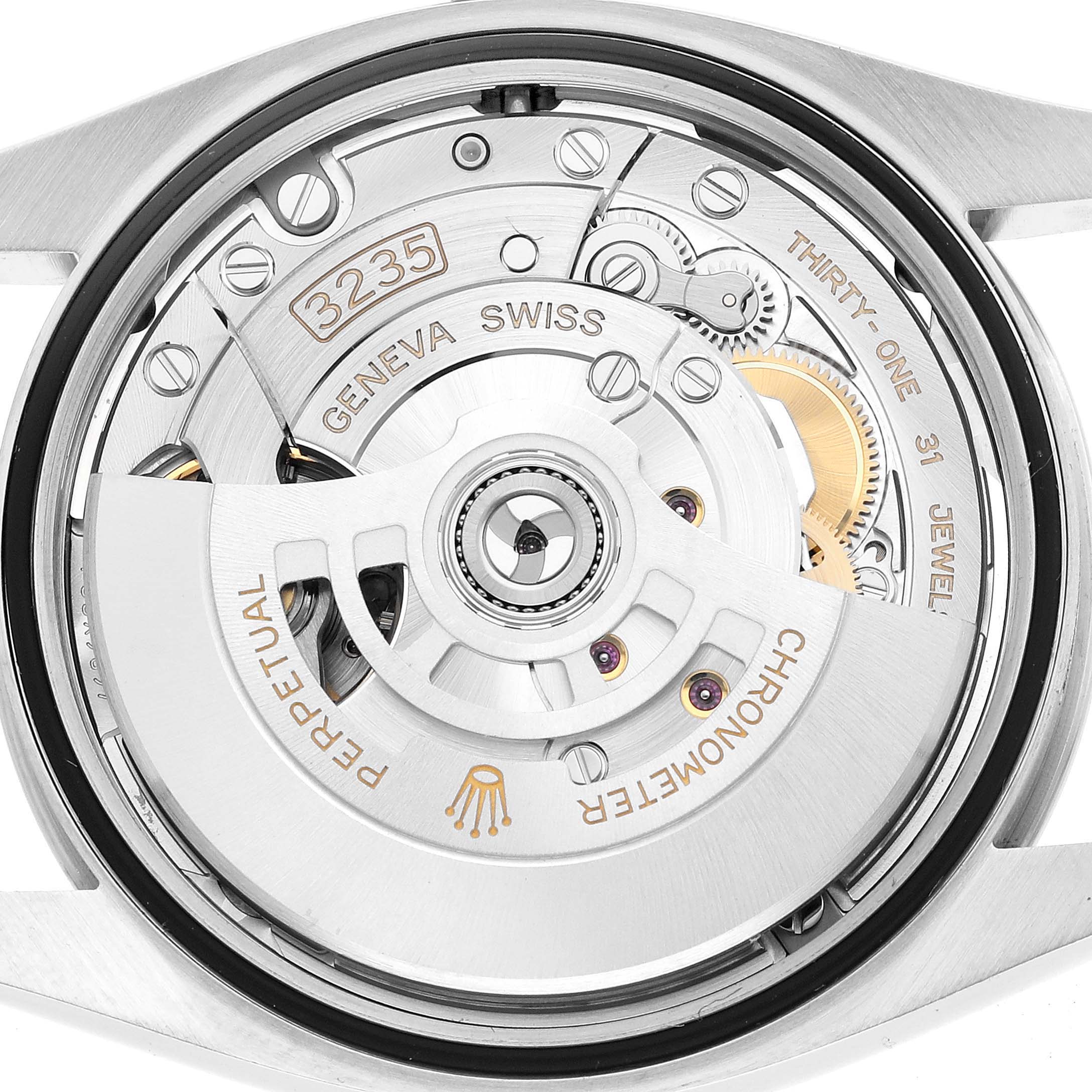 The image shows the movement of a Rolex Datejust 126200 Men's Stainless Steel White Dial watch, highlighting the rotor, gears, and jewels from the back.