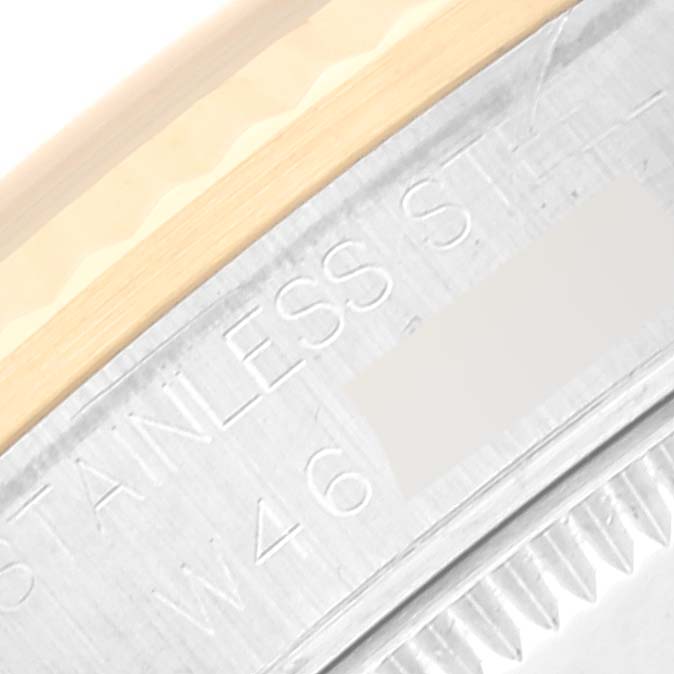 The image shows a Rolex Mid-Size 68273 Women's Steel and Gold (two tone) Black Dial 68273 Women's Steel and Gold (two tone) Black Dial watch’s edge of the case at an angled close-up, highlighting the "stainless steel" engraving.