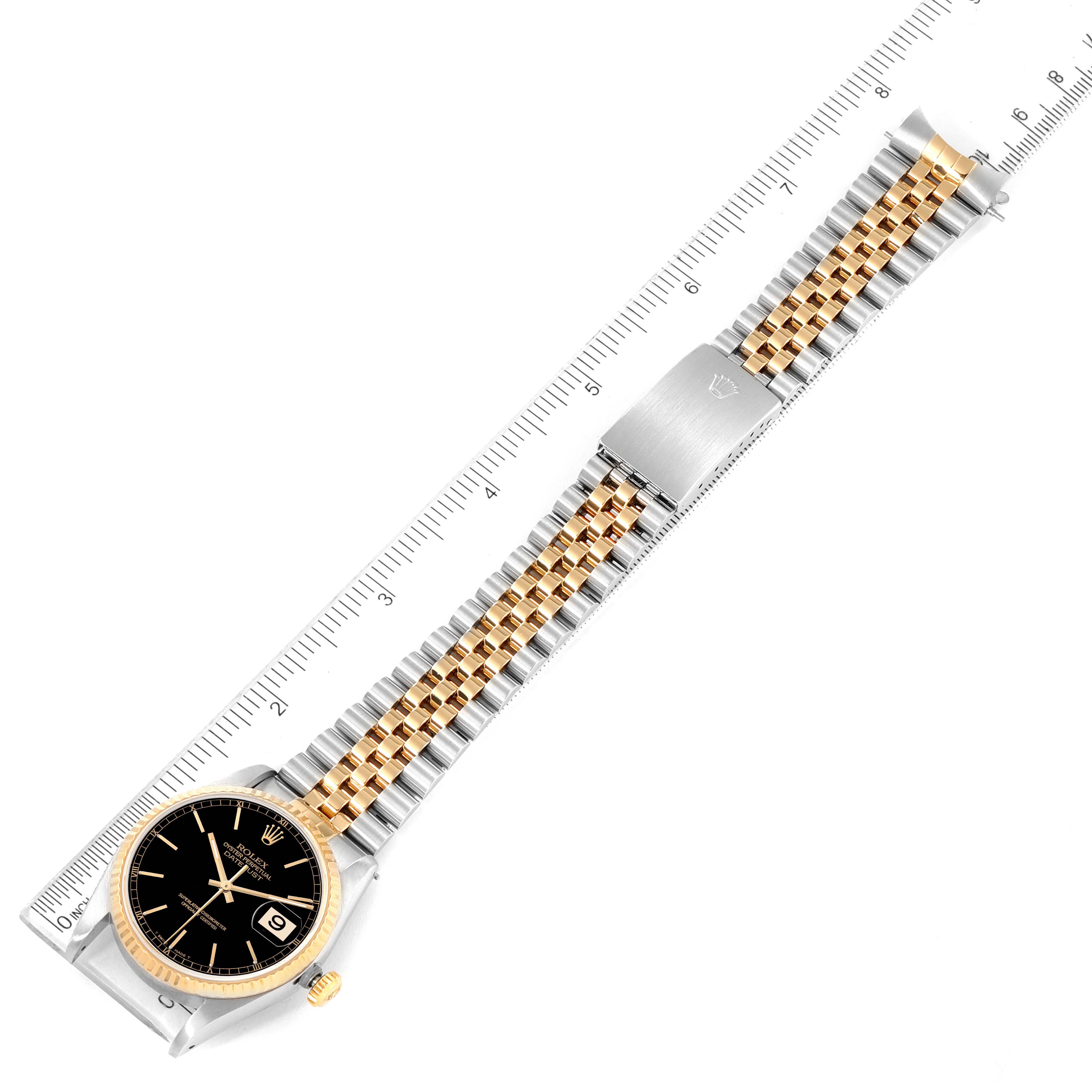 The image shows a Rolex Datejust 16233 Men's Steel and Gold (two tone) Black Dial 16233 Men's Steel and Gold (two tone) Black Dial watch, laid flat with its full bracelet visible alongside a ruler for scale.