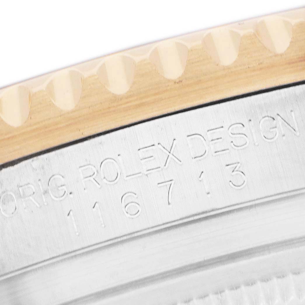 The image shows a close-up of the Rolex GMT-Master 116713 Men's Steel and Gold (two tone) Black Dial model's bezel and case, focusing on engraved details.