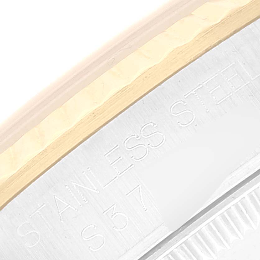 The image shows a close-up of the side profile of a stainless steel bezel of a Mid-Size Rolex watch with partial engravings visible.