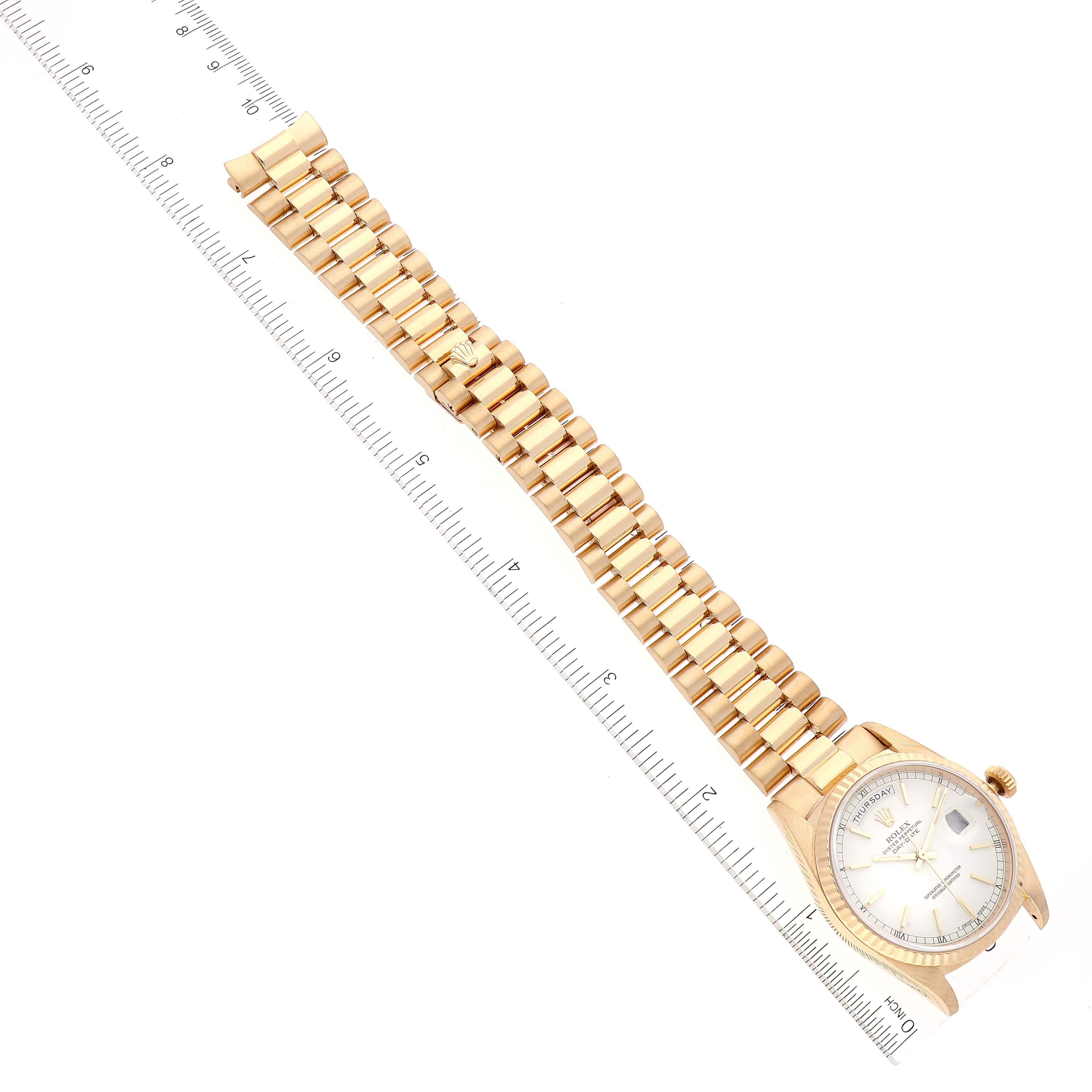 The image shows a Rolex President 18238 Men
s Yellow Gold White Dial 18238 Men
s Yellow Gold White Dial model watch, viewed from above, displaying the bracelet and face aligned with a measuring ruler.