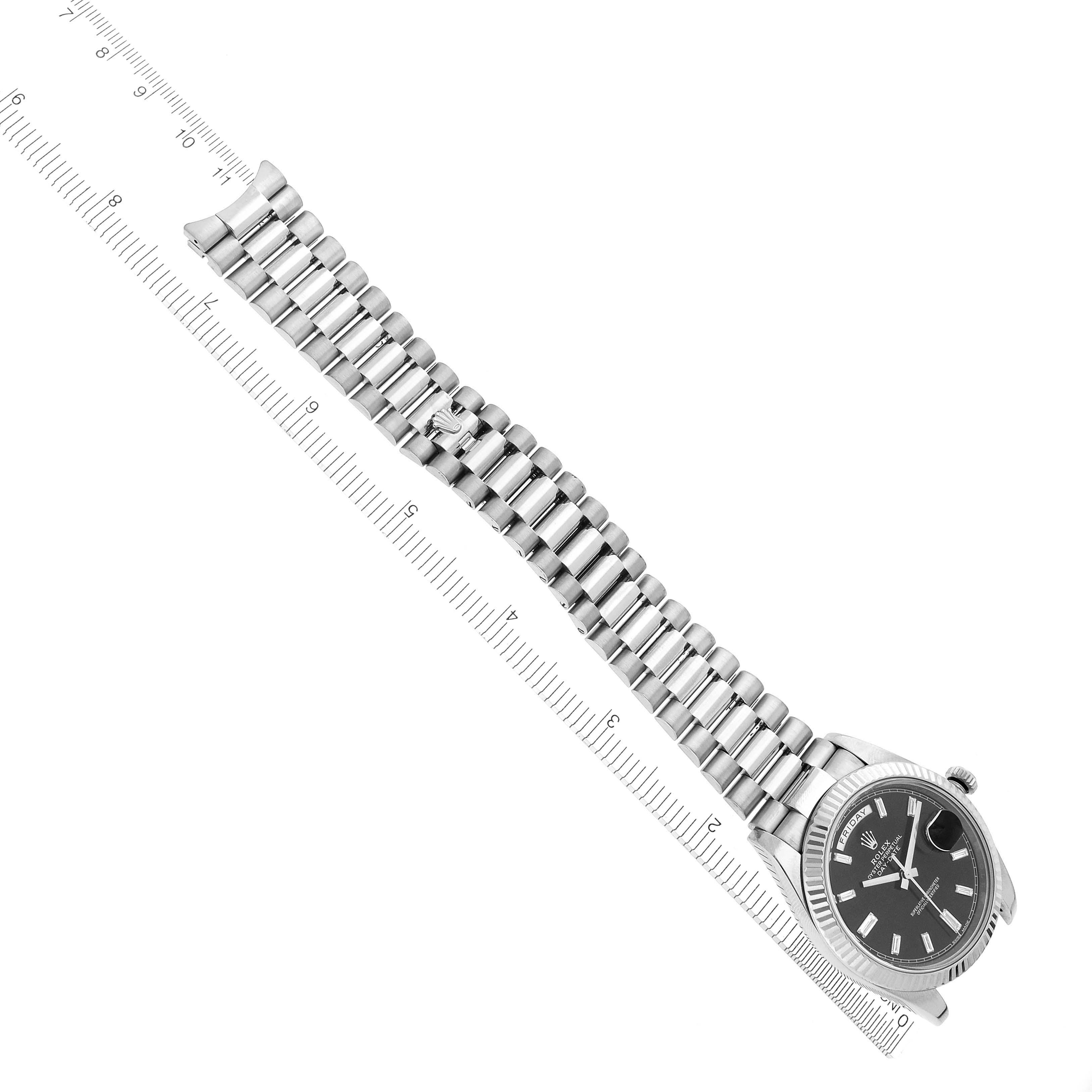 The Rolex President 228239 Men's White Gold Black Dial 228239 Men's White Gold Black Dial model watch is shown from a top-down angle, with its face and bracelet visible alongside a ruler.
