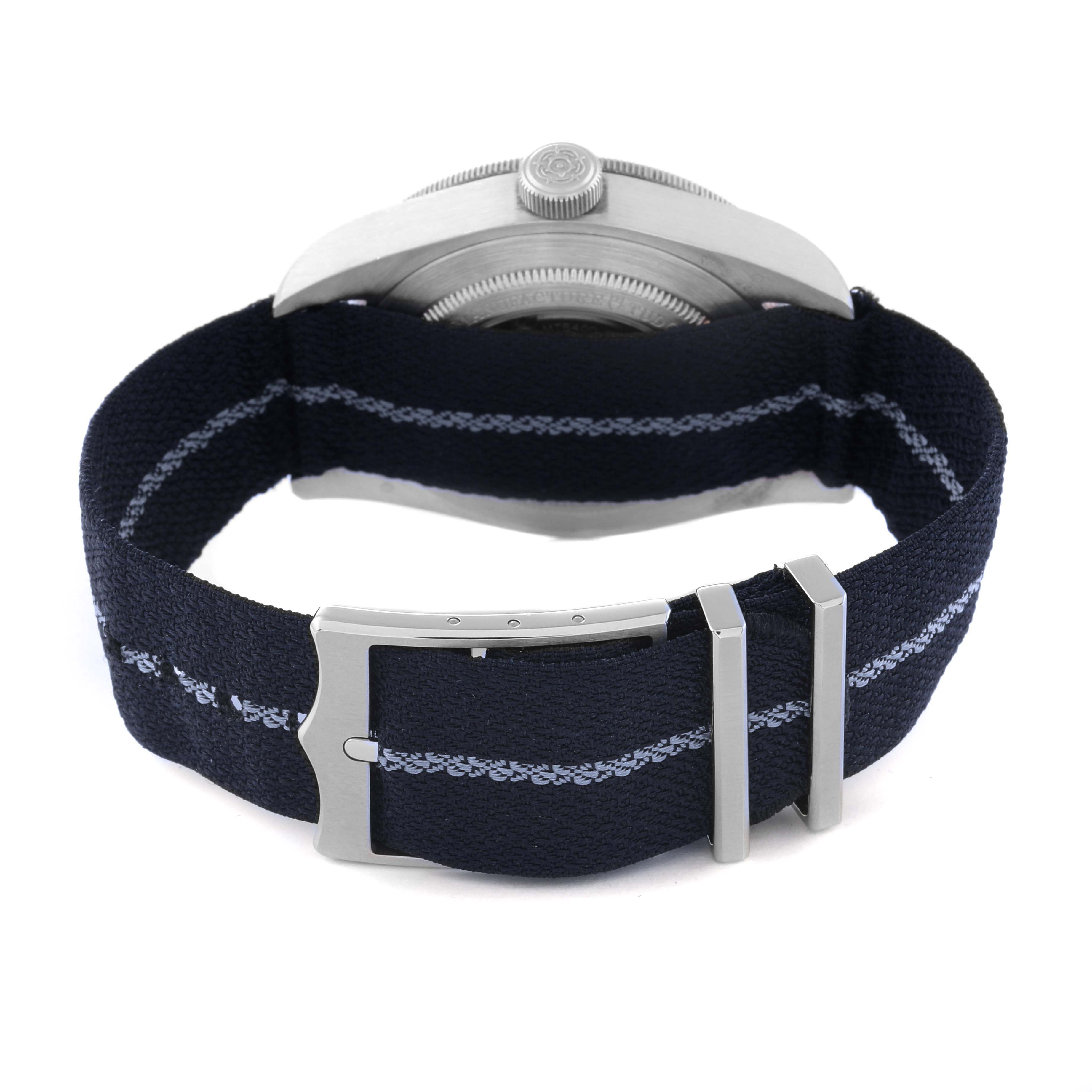 The image shows the back view of the Tudor Heritage Black Bay 79010SG Men
s Stainless Steel Grey Dial 79010SG Men
s Stainless Steel Grey Dial watch with a fabric strap and metal clasp.