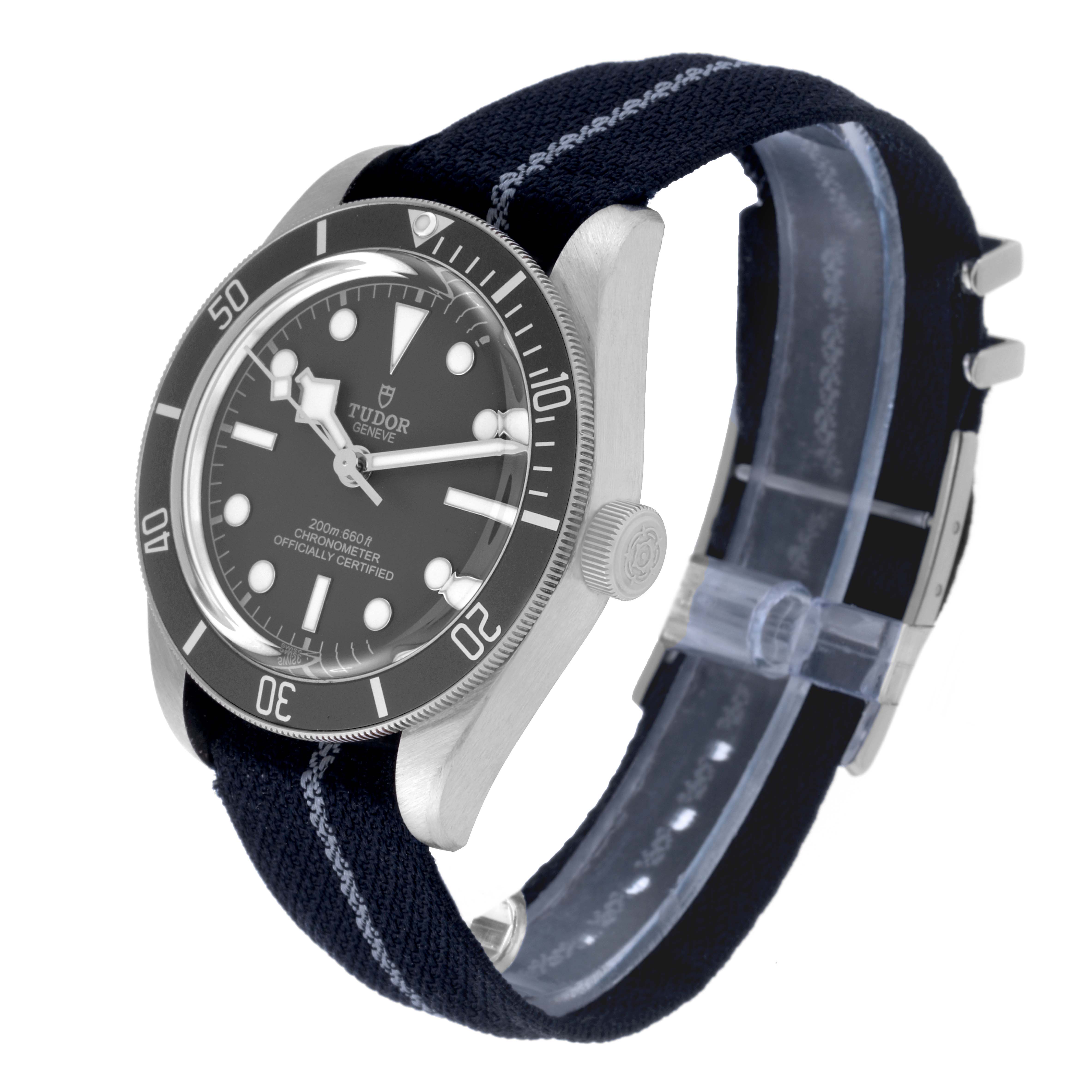 The image shows a Heritage Black Bay watch by Tudor at an angled side view, highlighting the face, bezel, crown, and fabric strap.