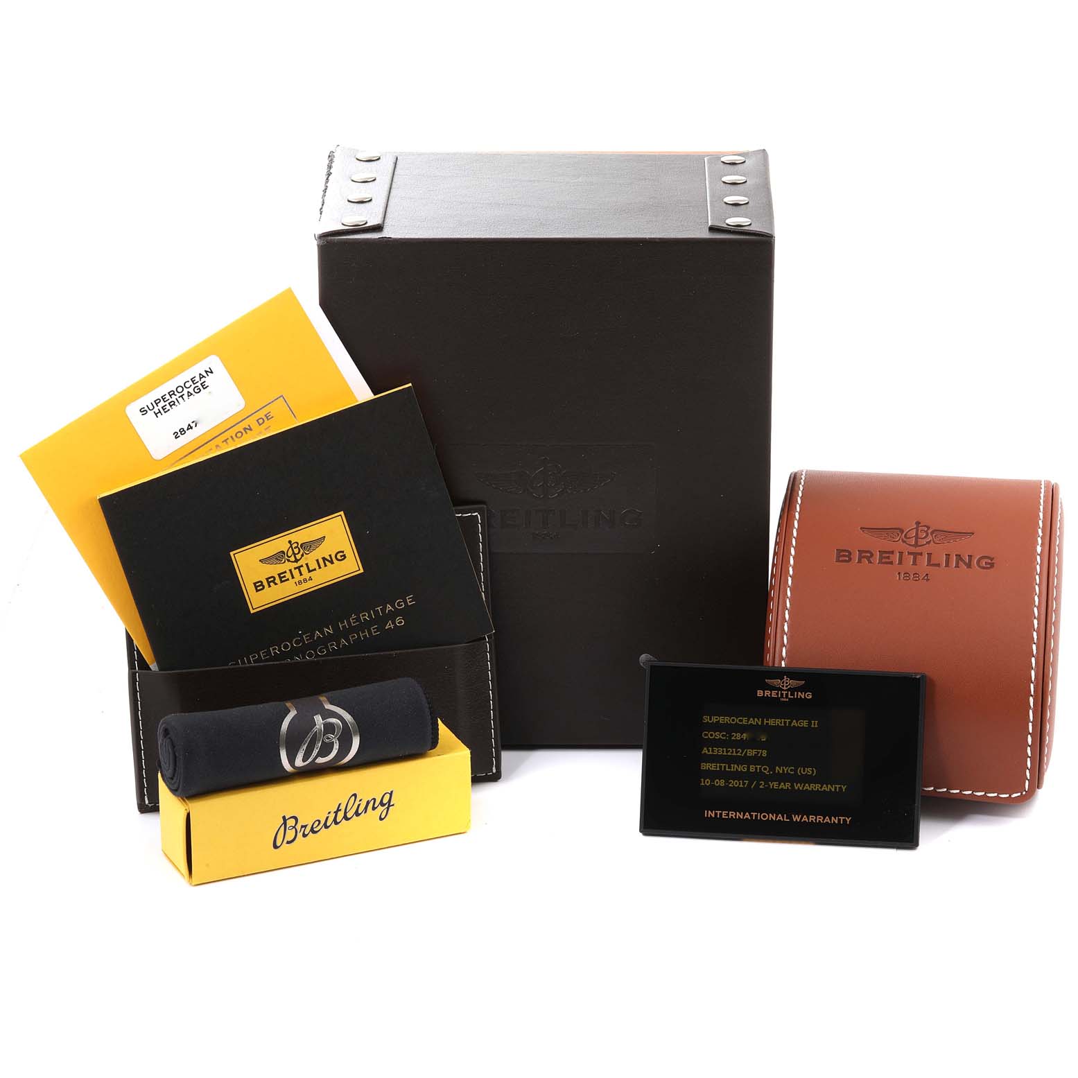 The image shows Breitling Superocean A13312 Men
s Stainless Steel Black Dial watch accessories, including a box, cases, manuals, a cleaning cloth, and a warranty card.