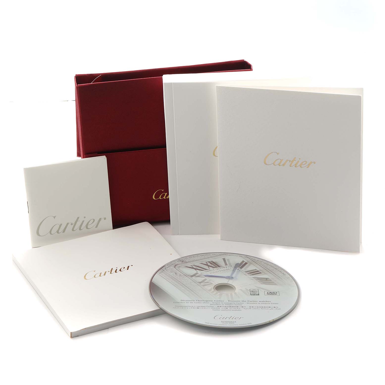 The image shows watch accessories for the Cartier Tank Americaine WJTA0002 Women
s Rose Gold Silver Dial, including boxes, booklets, and a CD.