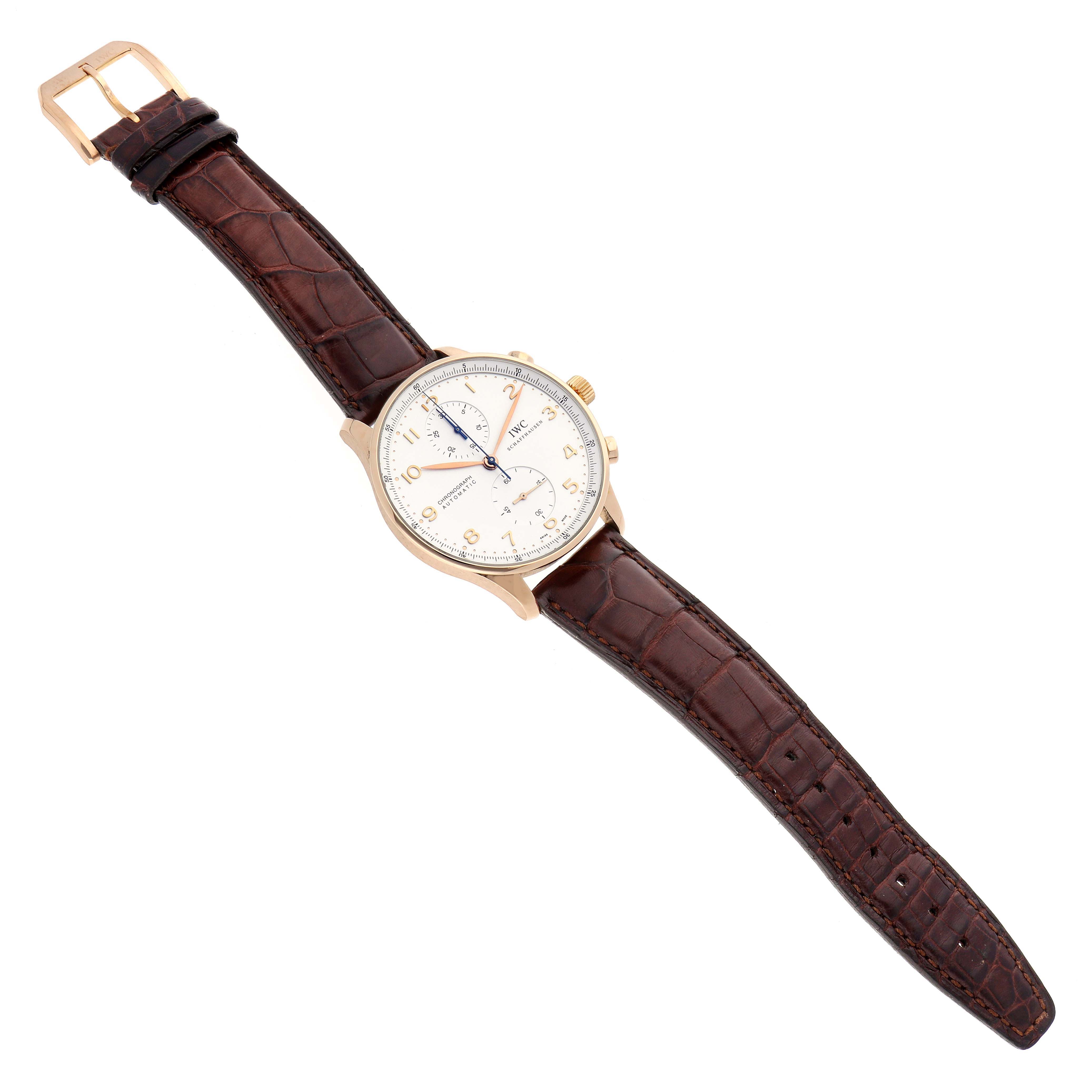 The IWC Portuguese IW371480 Men
s Rose Gold Silver Dial watch is shown from a top-down angle, featuring a cream dial and brown leather strap.