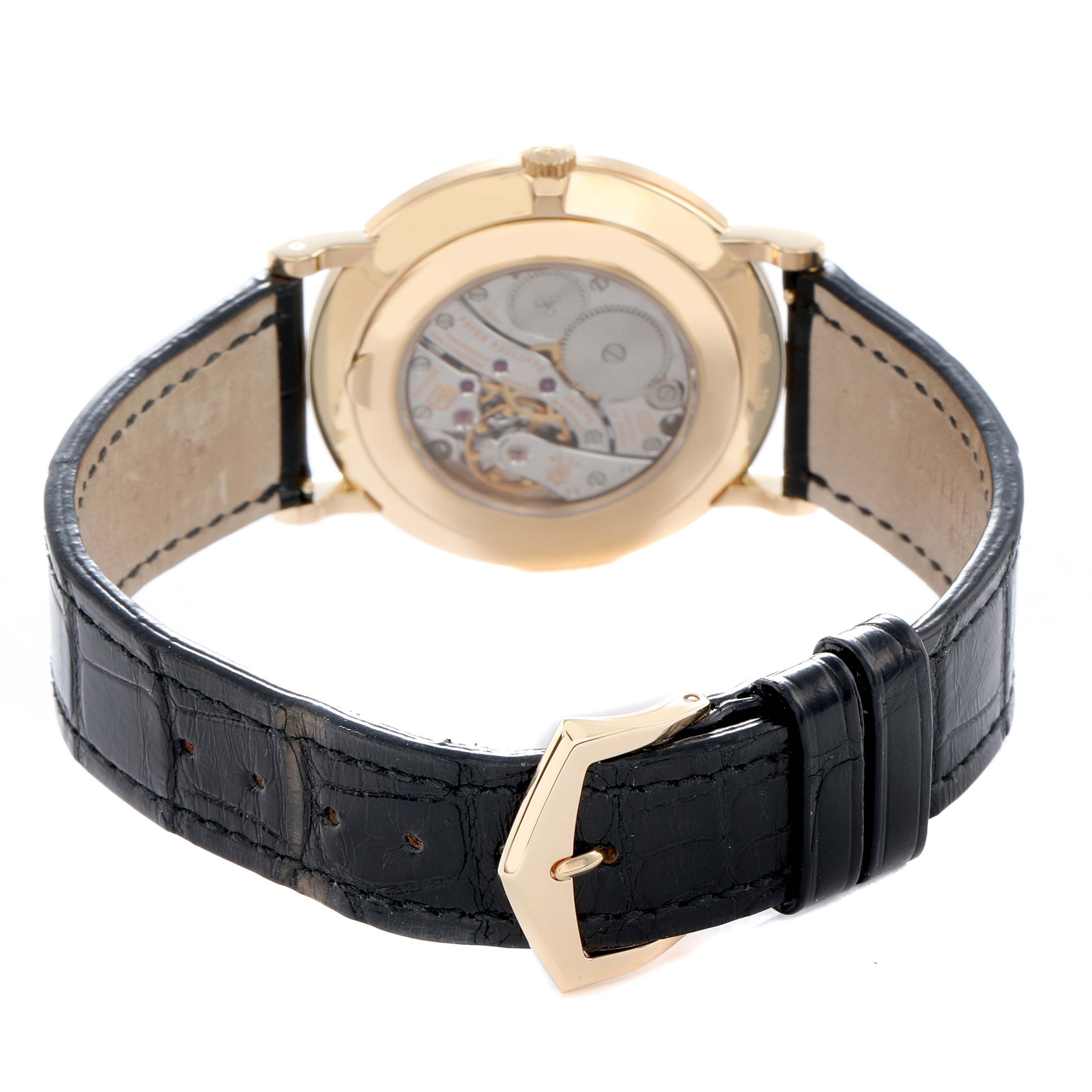 The Patek Philippe Calatrava 5119J-001 Men
s Yellow Gold White Dial watch is shown from the back, displaying its movement through a transparent case back and featuring a black leather strap.