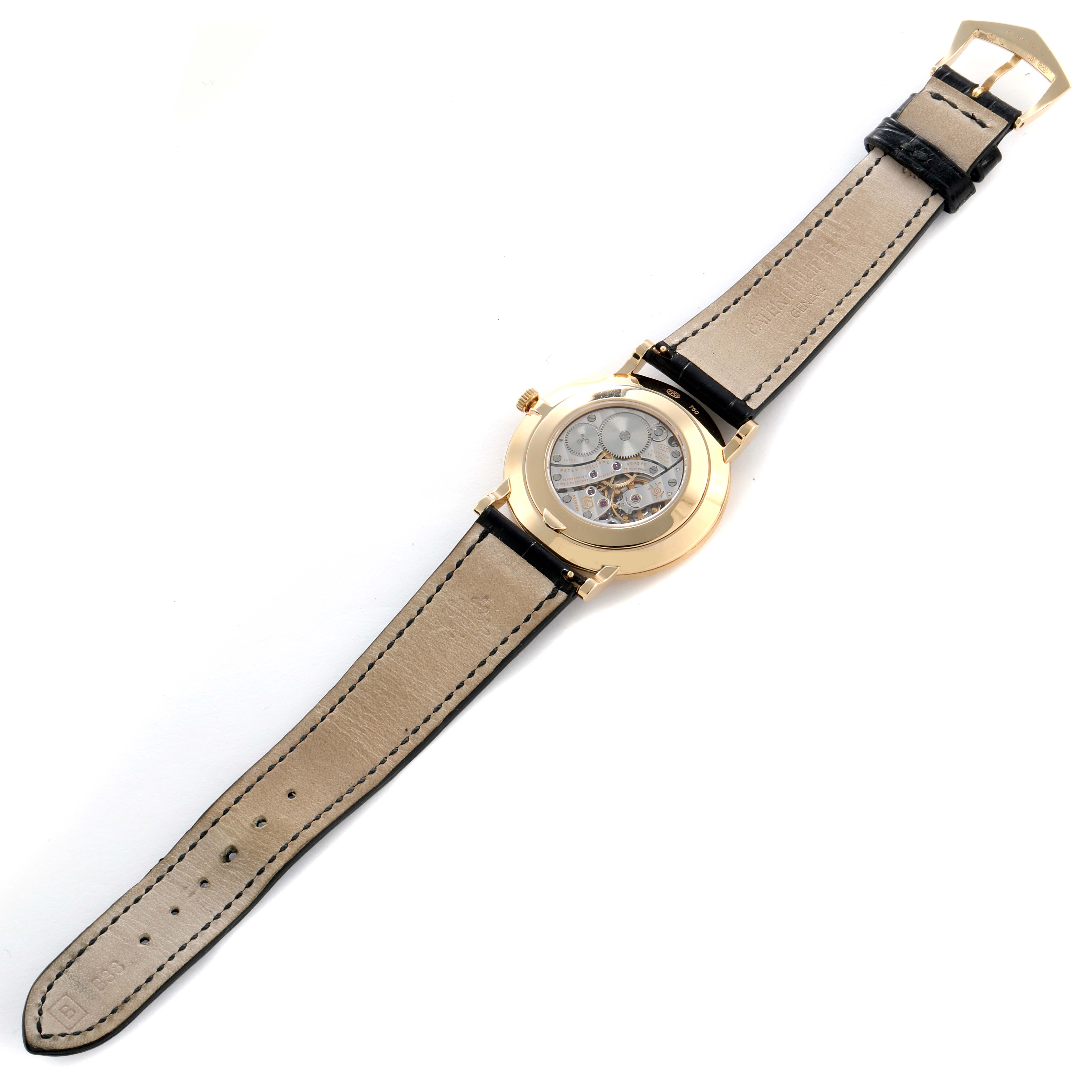 The Patek Philippe Calatrava 5119J-001 Men
s Yellow Gold White Dial watch is shown from the back, highlighting the movement through the transparent case back and leather strap.