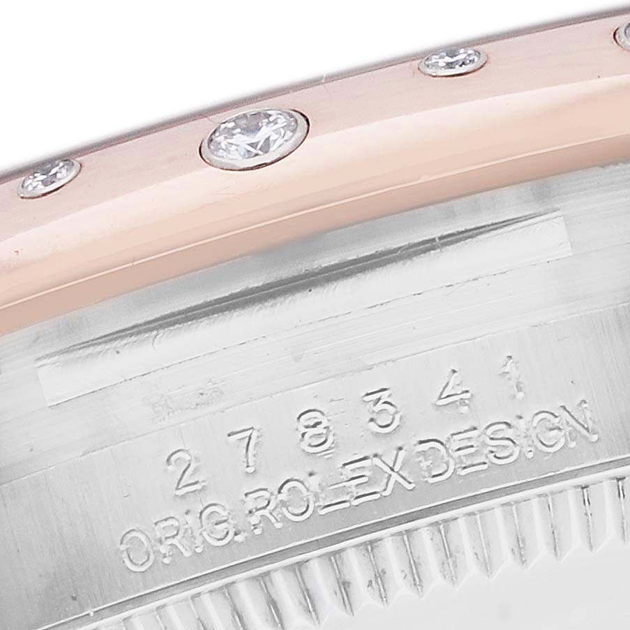 The image shows a close-up of a Rolex Mid-Size 278341 Women
s Steel and Gold (two tone) Mother of Pearl Dial model bezel with diamonds and a portion of the engraved case side.