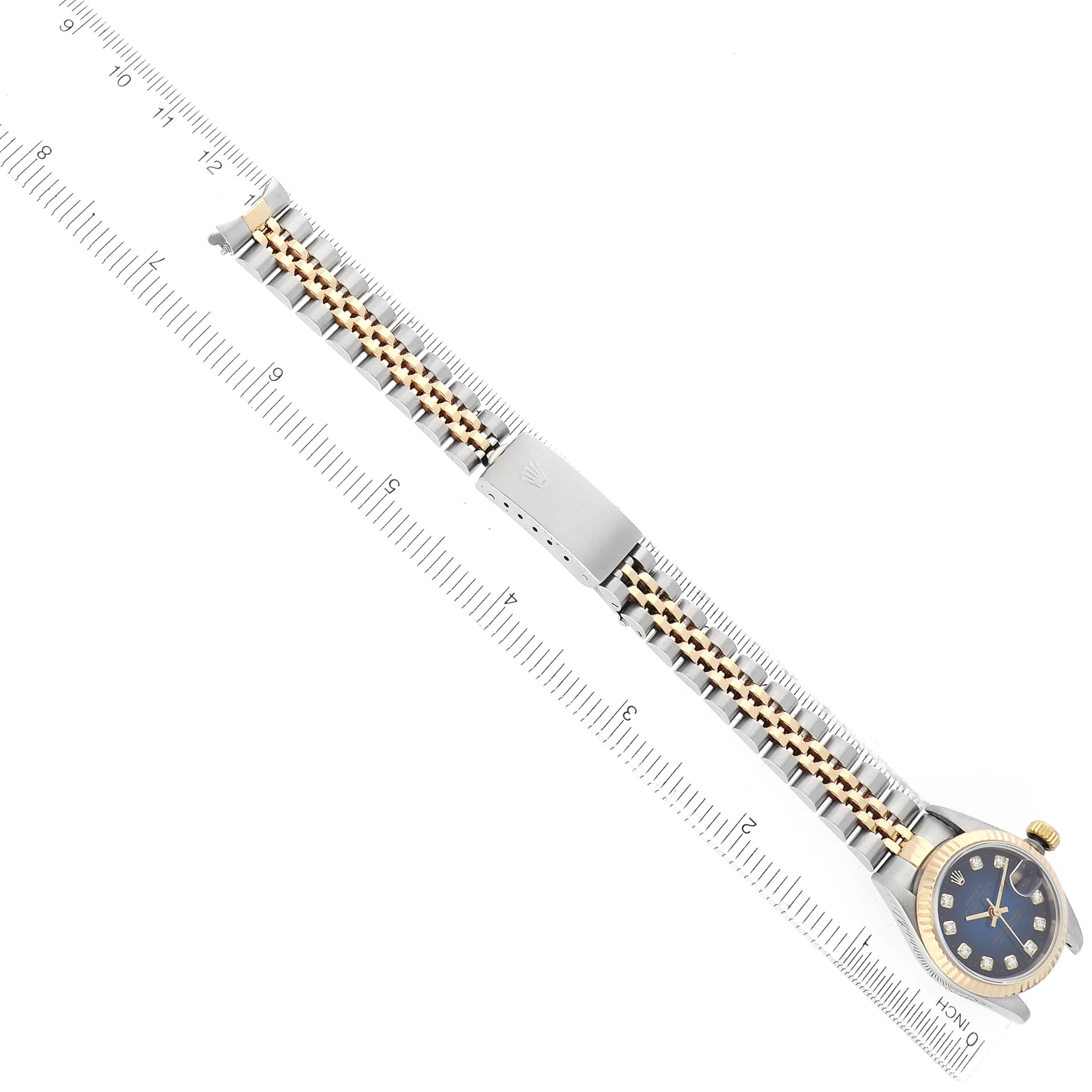 The Rolex Datejust 69173 Men
s Steel and Gold (two tone) Blue Dial watch is shown from a top view, highlighting the face, bezel, and bracelet against a ruler for scale.