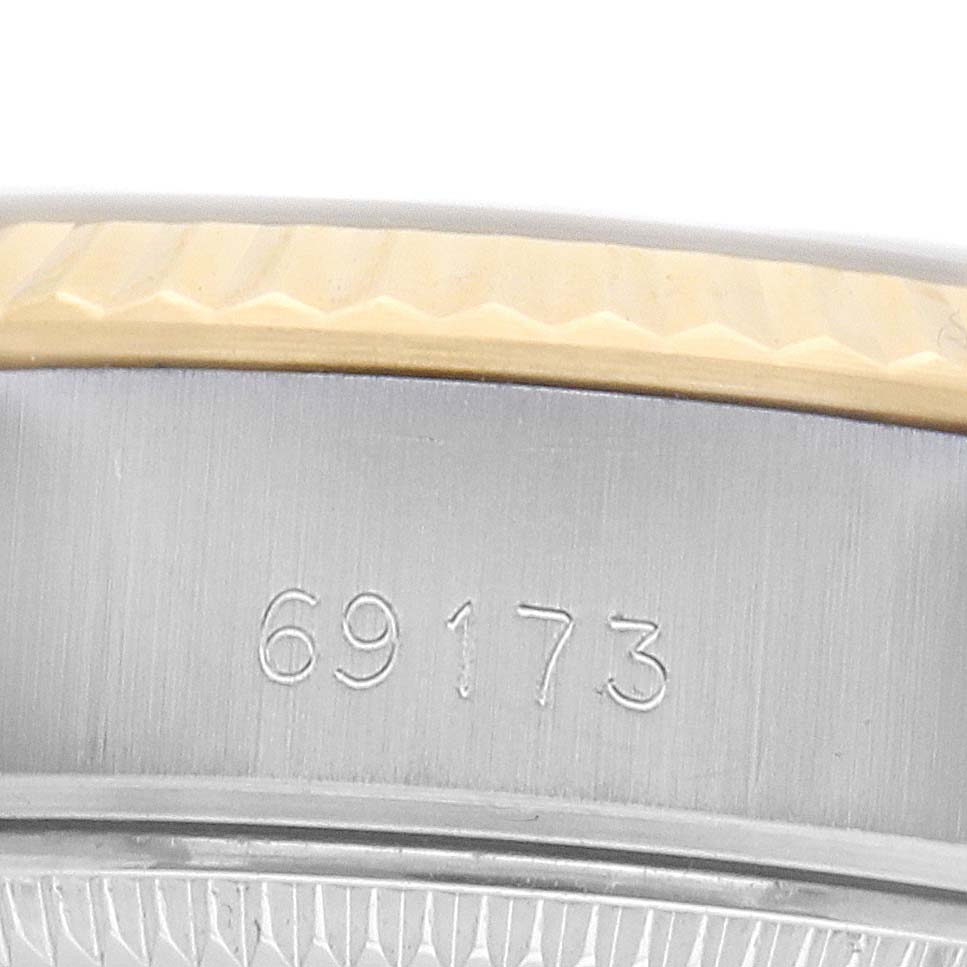 The image shows the side view of a Rolex Datejust 69173 Women
s Steel and Gold (two tone) Silver Dial, highlighting the serial number and the fluted bezel edge.