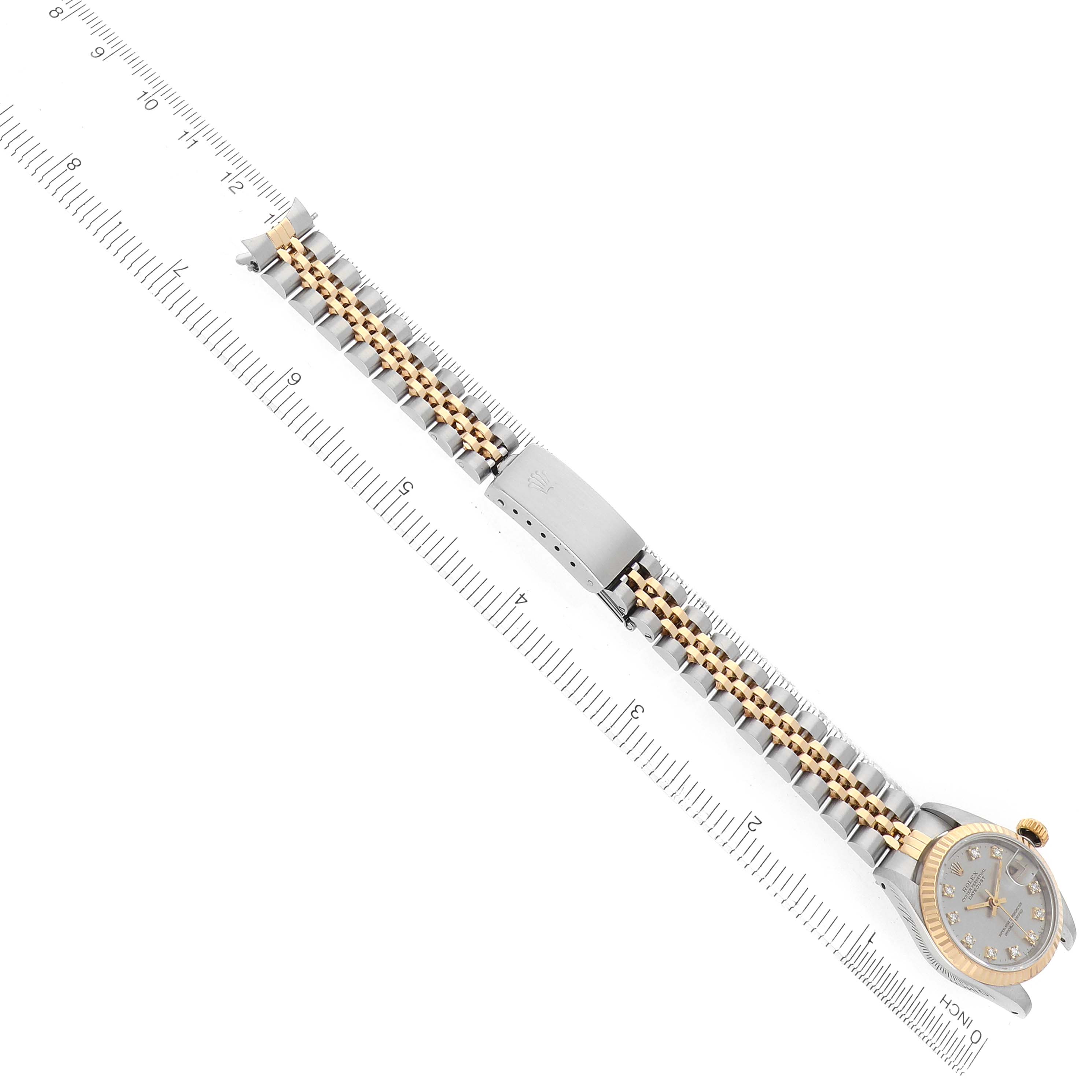 The image shows the Rolex Datejust 69173 Women
s Steel and Gold (two tone) Silver Dial watch from a top angle, highlighting the bracelet, clasp, and watch case with a ruler for scale.