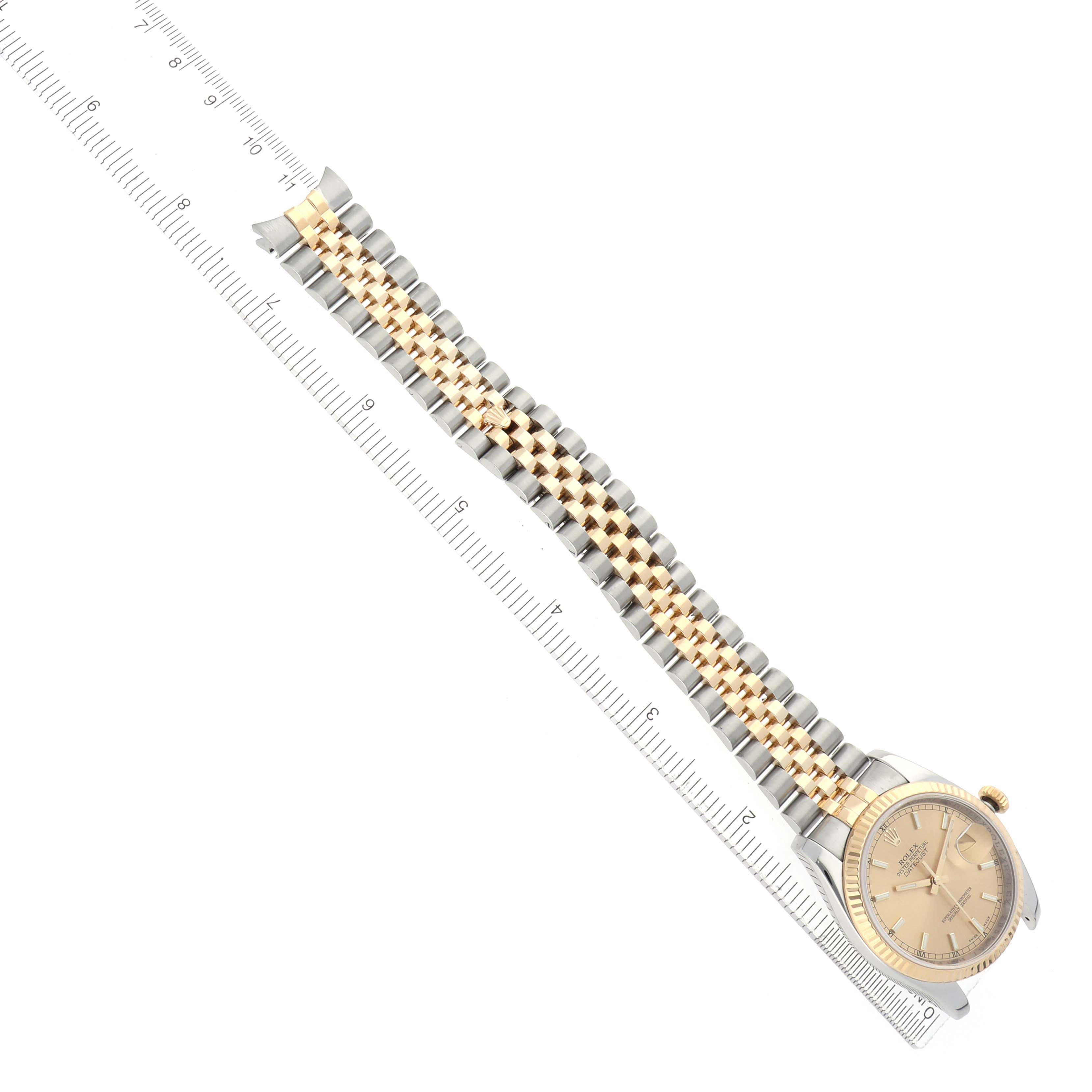 The Rolex Datejust 116233 Men
s Steel and Gold (two tone) Champagne Dial watch is shown from a top-down angle, displaying the face, bezel, and full bracelet alongside a ruler.