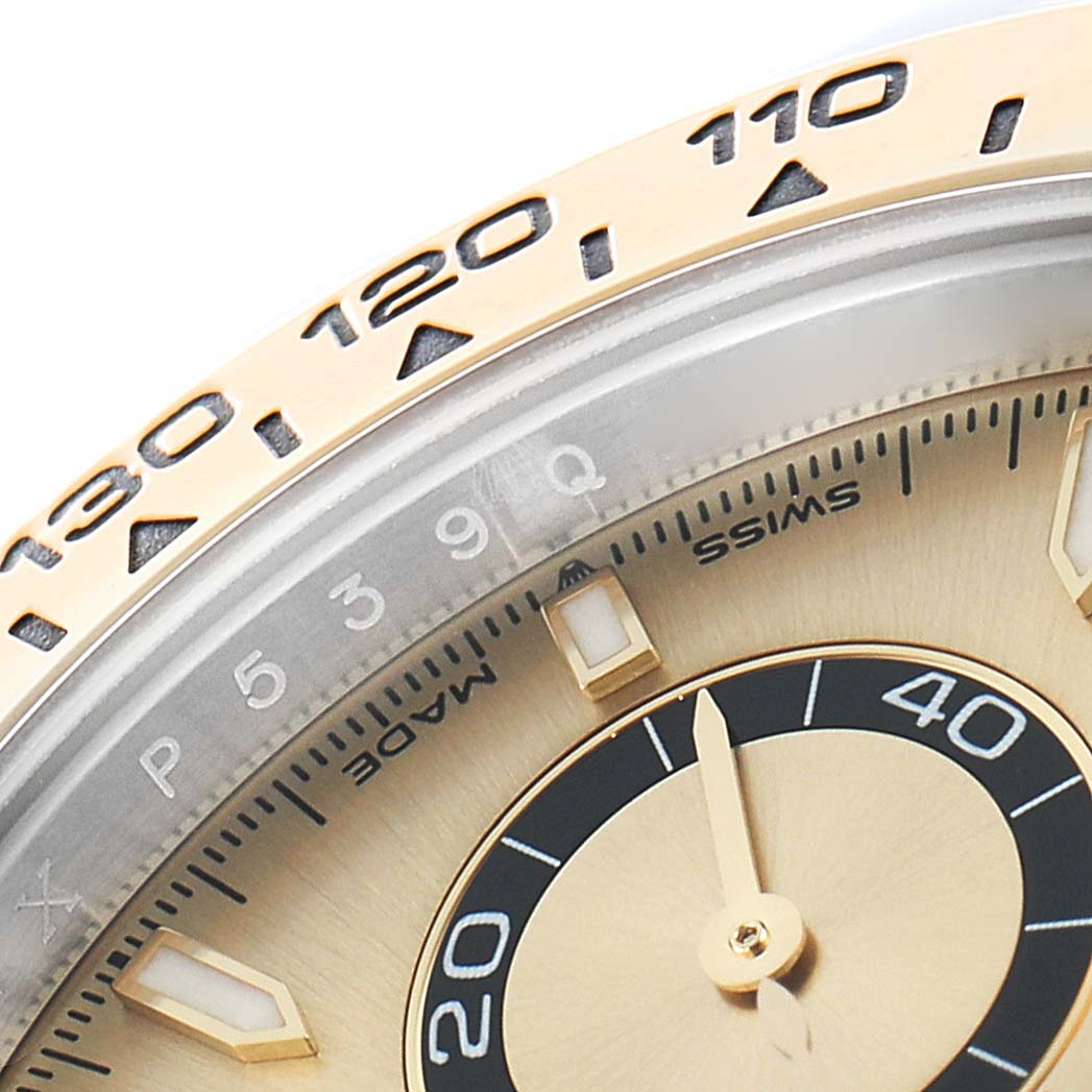 The image shows a close-up of the Rolex Daytona 126503 Men
s Steel and Gold (two tone) Champagne Dial
s bezel and part of the dial, highlighting the tachymetric scale and hour markers.