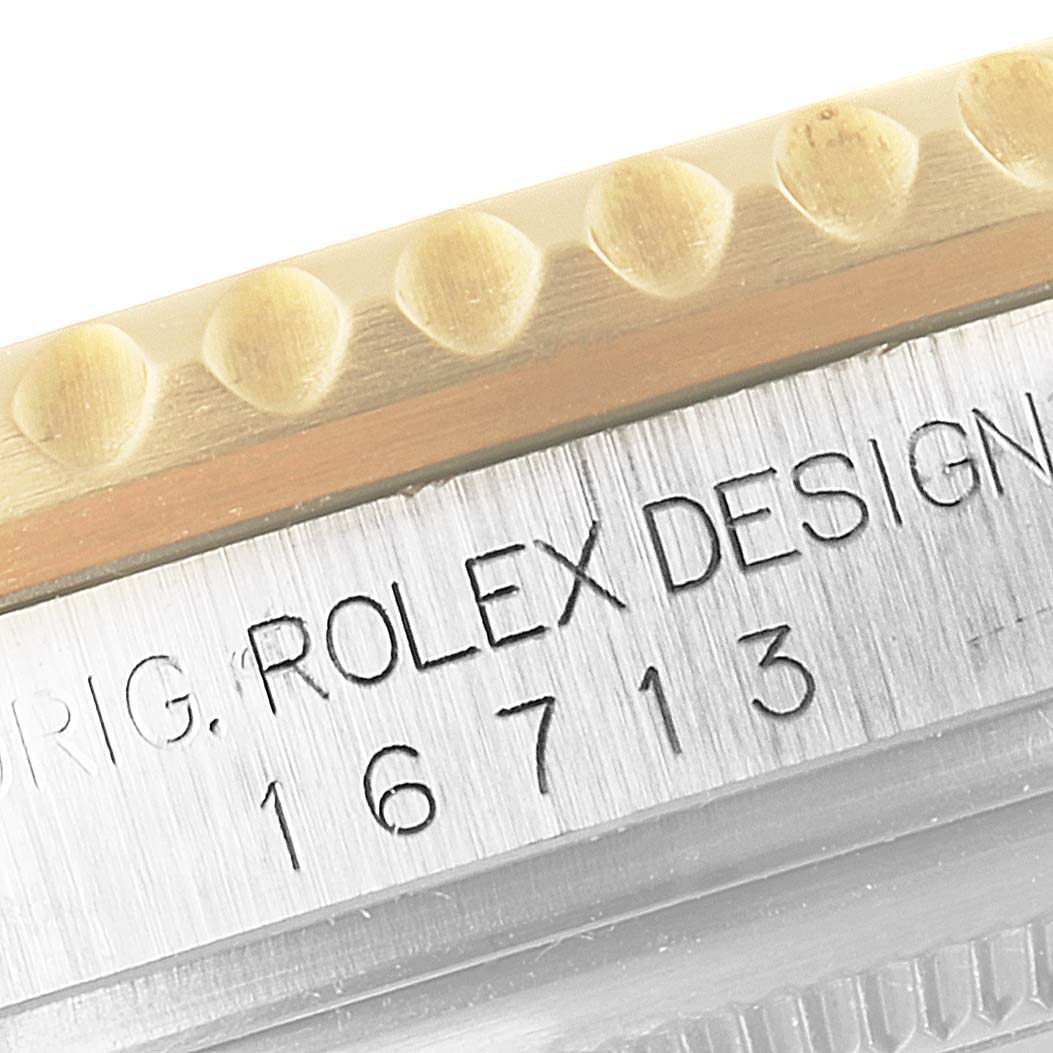 The image shows a close-up of the case side of a Rolex GMT-Master 16713 Men's Steel and Gold (two tone) Black Dial 16713 Men's Steel and Gold (two tone) Black Dial watch, featuring the bezel and engraved reference number.