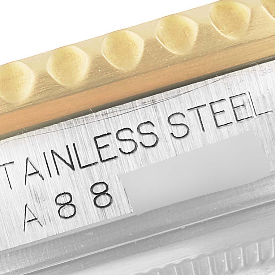 Close-up of the Rolex GMT-Master 16713 Men's Steel and Gold (two tone) Black Dial 16713 Men's Steel and Gold (two tone) Black Dial showing part of the stainless steel case and bezel edge with engraved text.