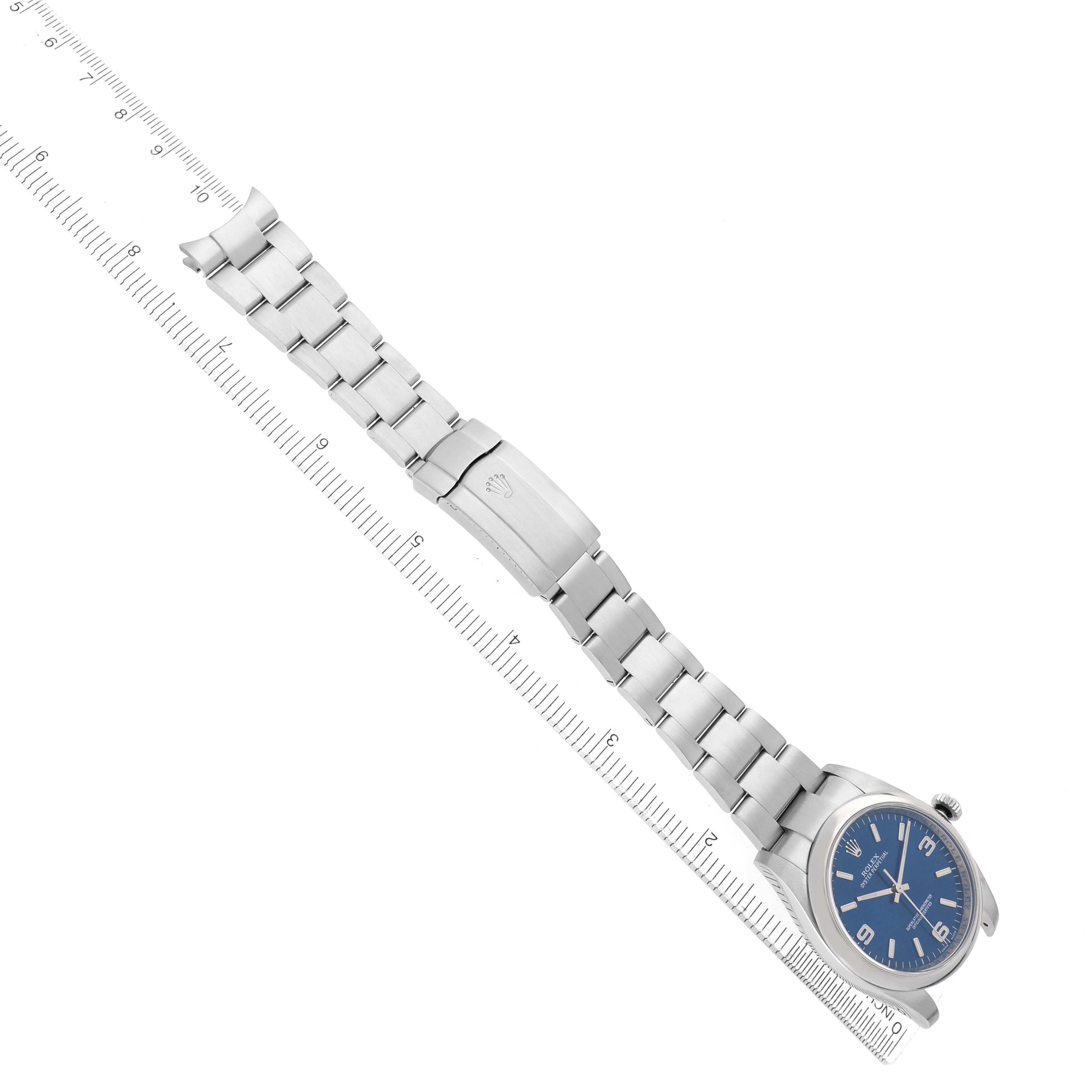 The Rolex Oyster Perpetual 116000 Men's Stainless Steel Blue Dial watch is shown at an angle displaying the full bracelet, clasp, and partial face with a blue dial.
