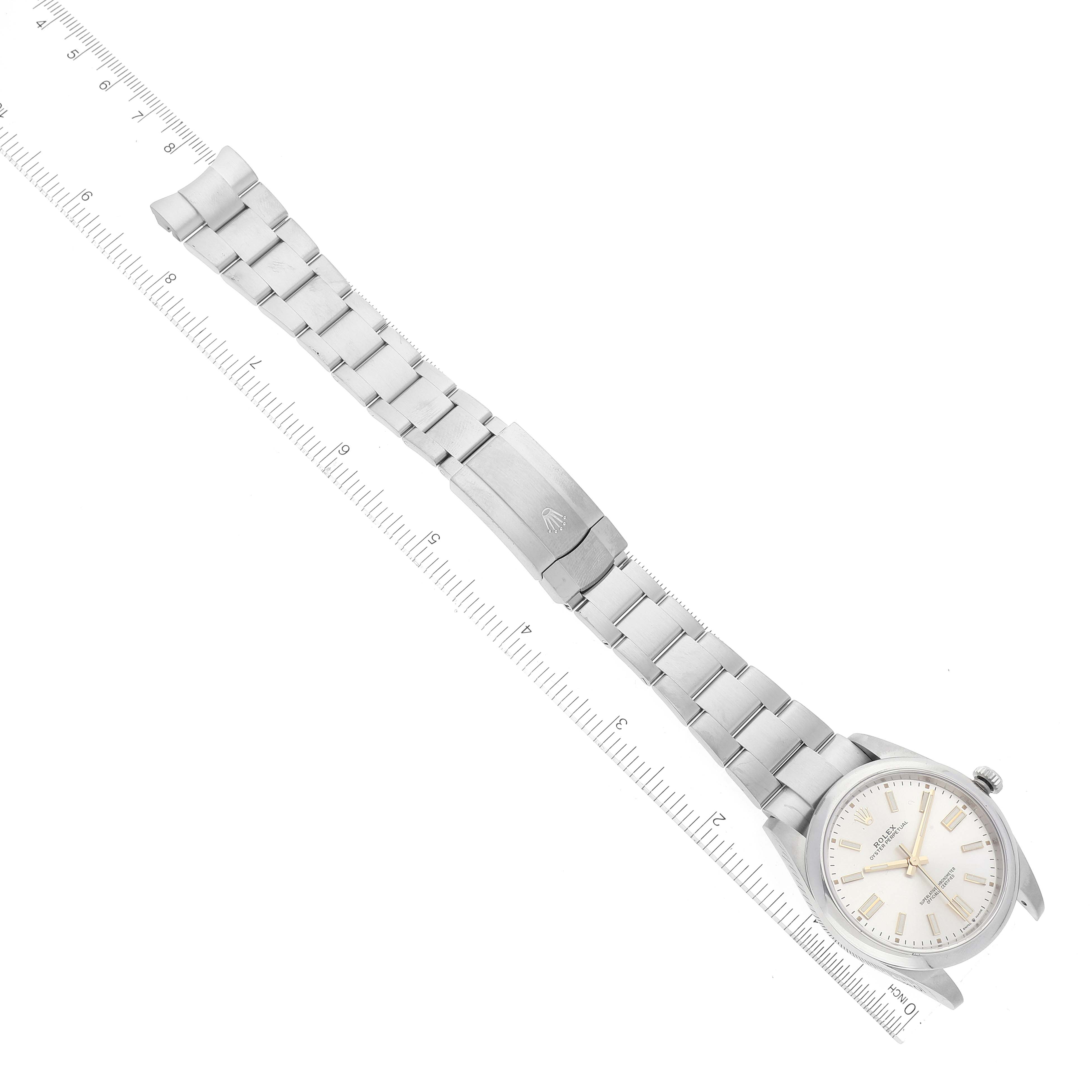 The image shows an overhead view of a Rolex Oyster Perpetual 124300 Men's Stainless Steel Silver Dial 124300 Men's Stainless Steel Silver Dial watch, displaying the bracelet, clasp, and face.