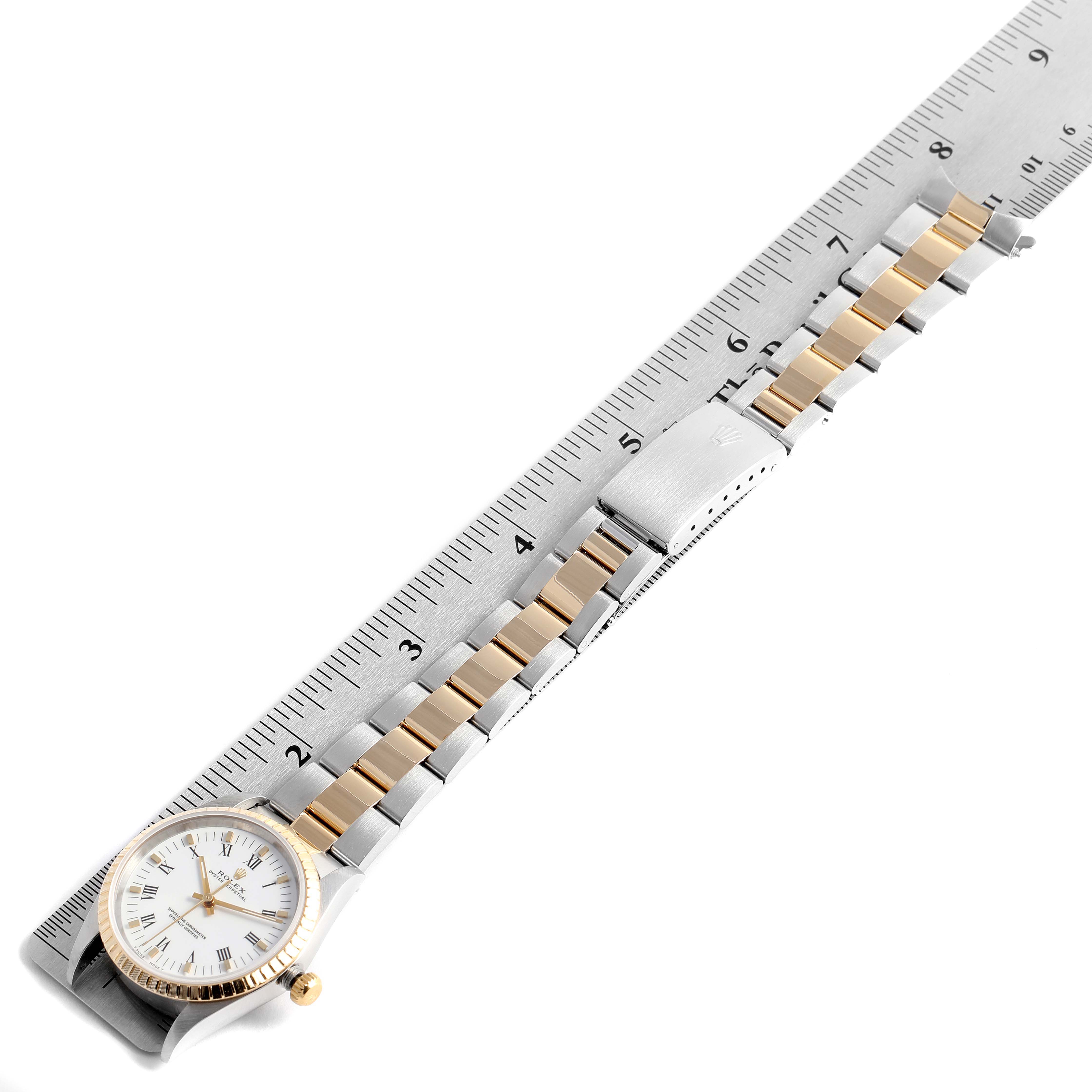 This image displays a top-down view of a Rolex Oyster Perpetual 14203 Men's Steel and Gold (two tone) White Dial 14203 Men's Steel and Gold (two tone) White Dial watch with its gold and silver bracelet fully extended alongside a ruler.