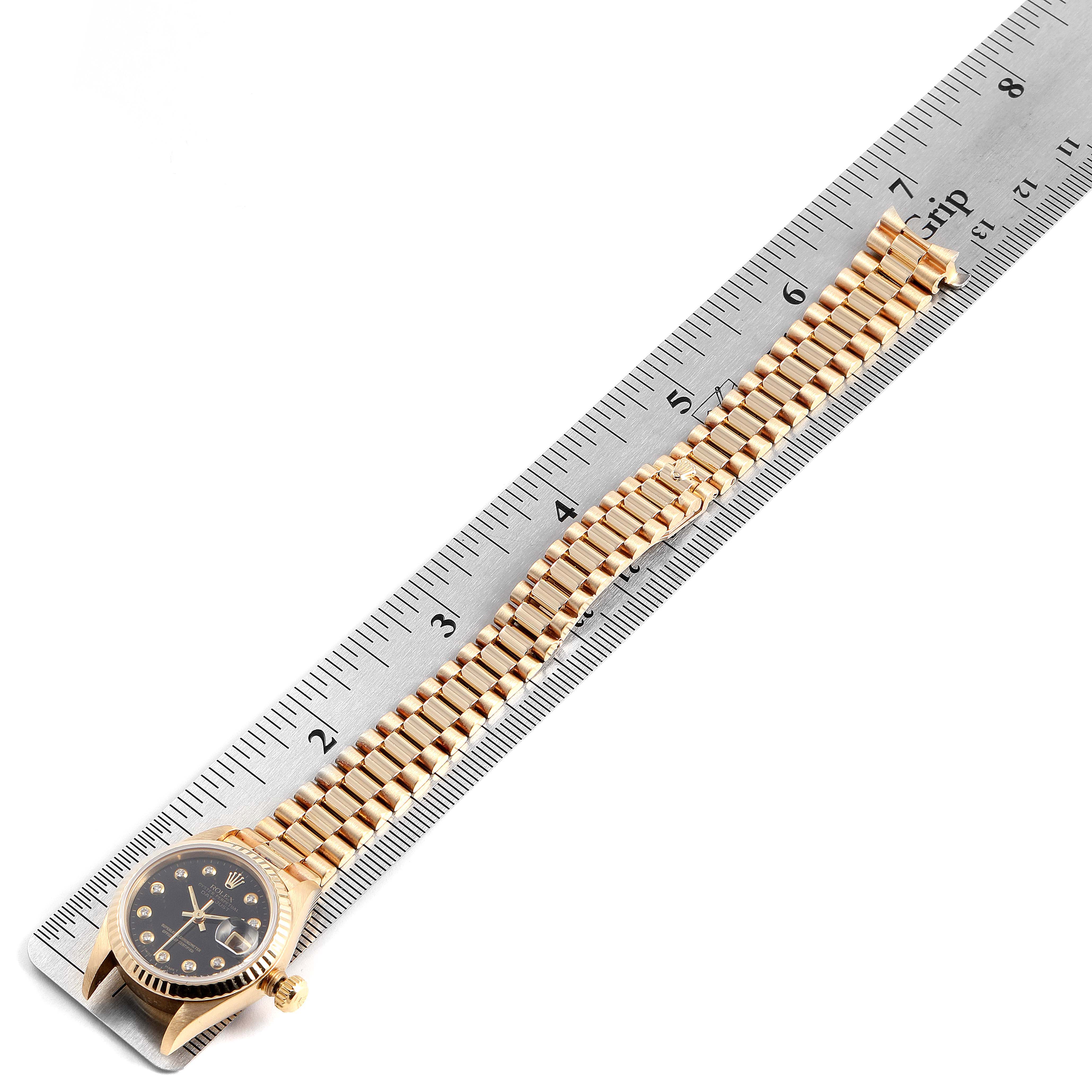 The image shows a Rolex President 69178 Women's Yellow Gold Black Dial 69178 Women's Yellow Gold Black Dial model watch from a top-down angle, lying next to a ruler.