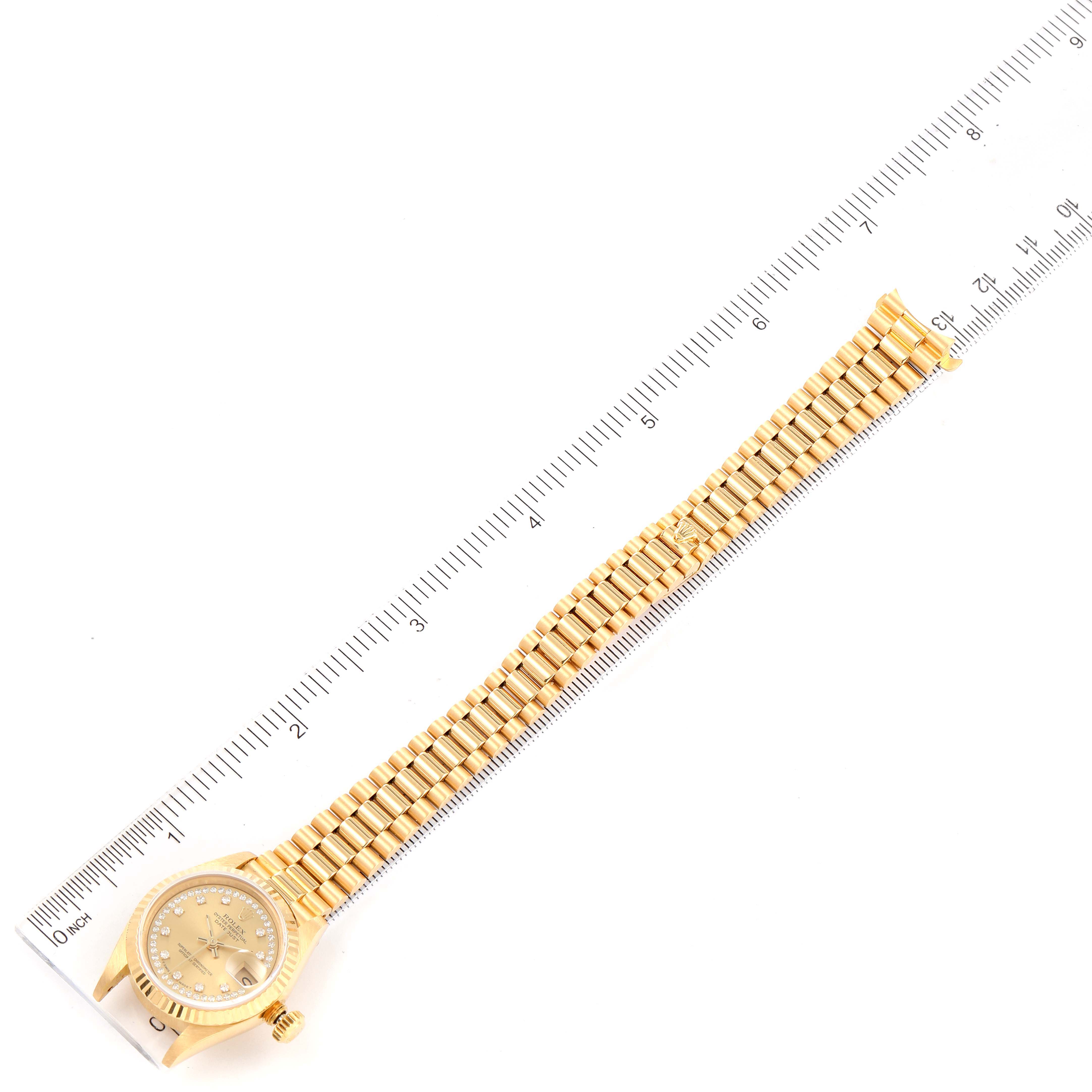 The Rolex President 69178 Women's Yellow Gold Champagne Dial 69178 Women's Yellow Gold Champagne Dial model watch is shown laid flat, fully extended, with a ruler next to it for scale.