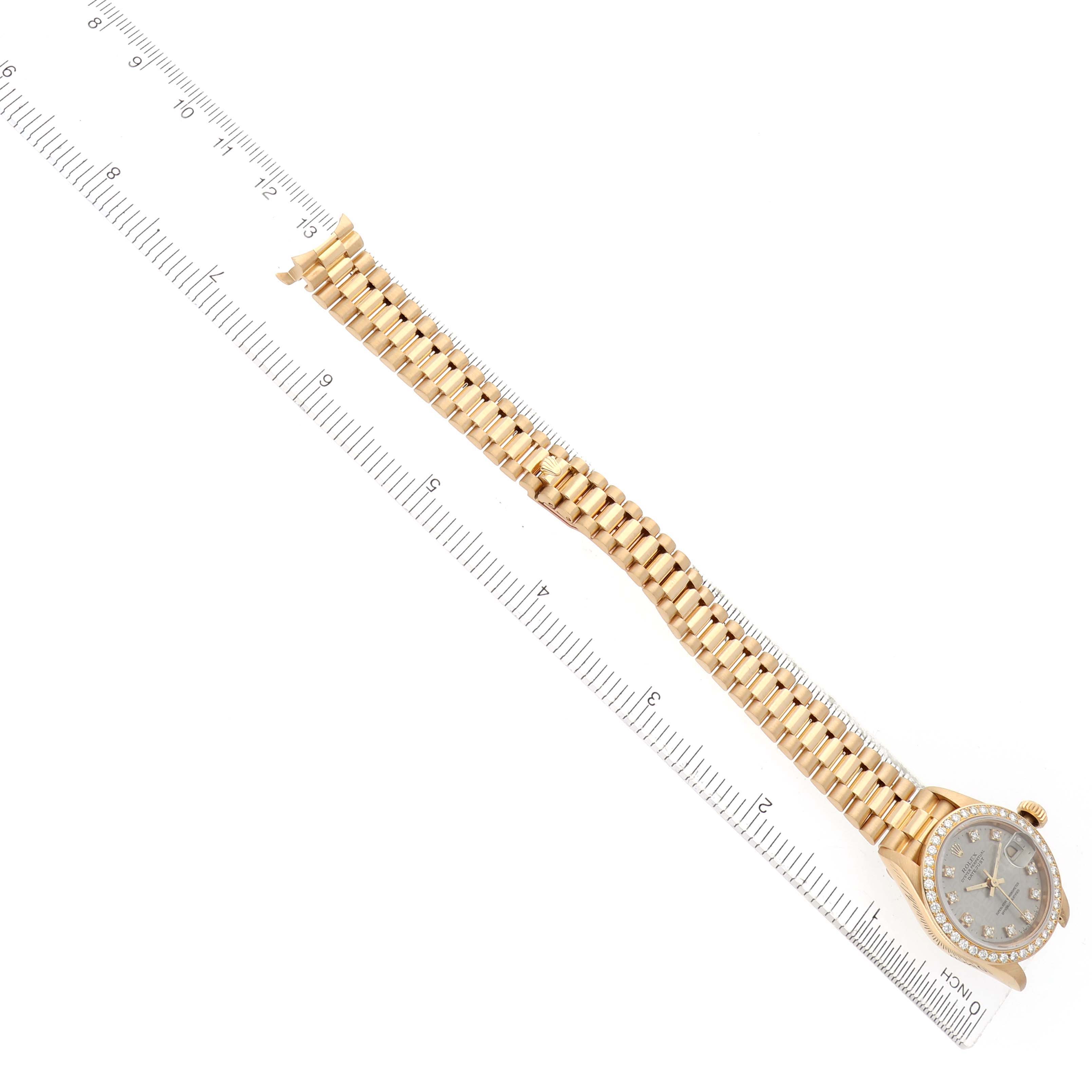 The Rolex President 69138 Women
s Yellow Gold Silver Dial watch is shown from a top view, highlighting its bracelet and face, with a ruler for scale.
