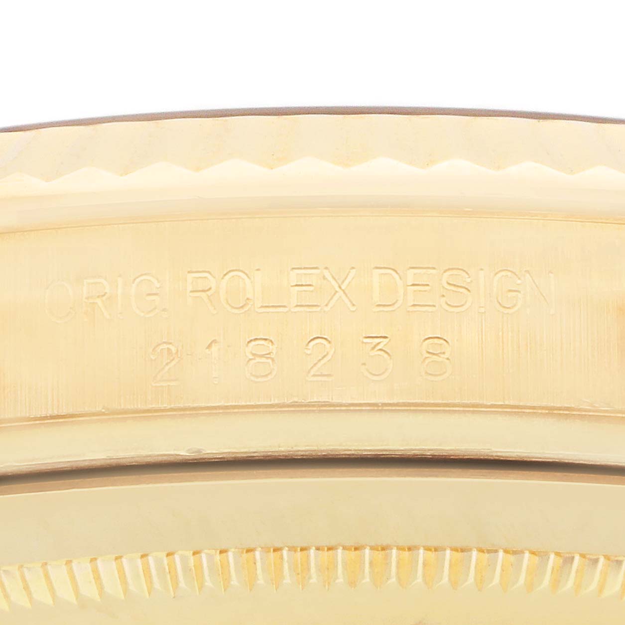 The image shows the edge of a gold Rolex President 218238 Men
s Yellow Gold Champagne Dial model, displaying its engraved serial number.
