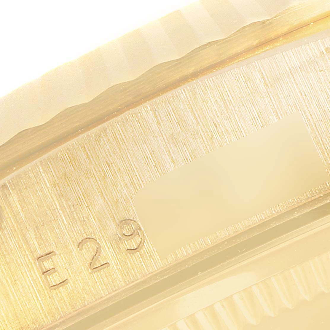 This image shows a close-up of the side edge of a Rolex President 18238 Men
s Yellow Gold Champagne Dial 18238 Men
s Yellow Gold Champagne Dial watch, highlighting part of the bezel and serial number.