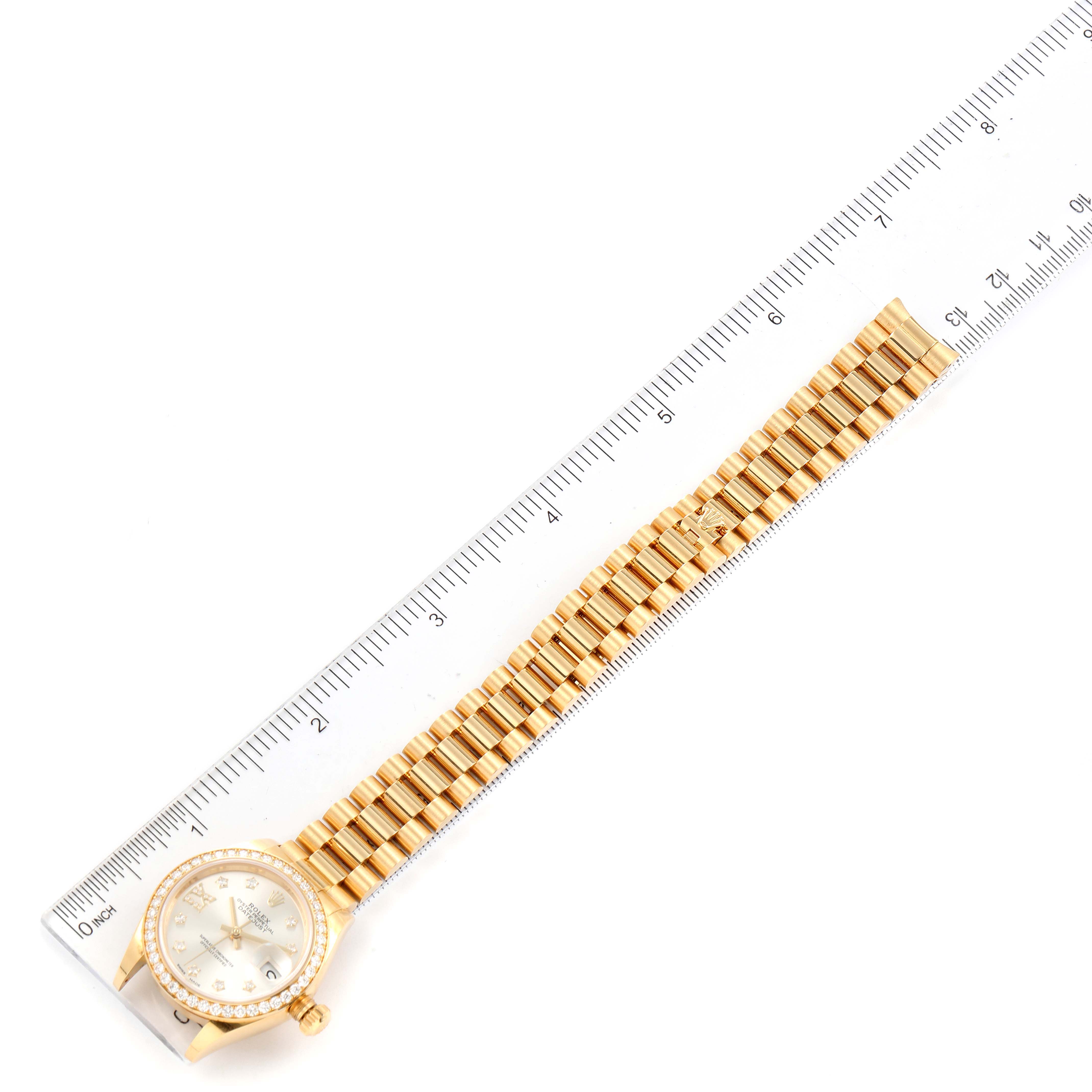 This image shows the Rolex President 279138 Women's Yellow Gold Silver Dial 279138 Women's Yellow Gold Silver Dial model watch laid flat beside a ruler, displaying its full length and band links.