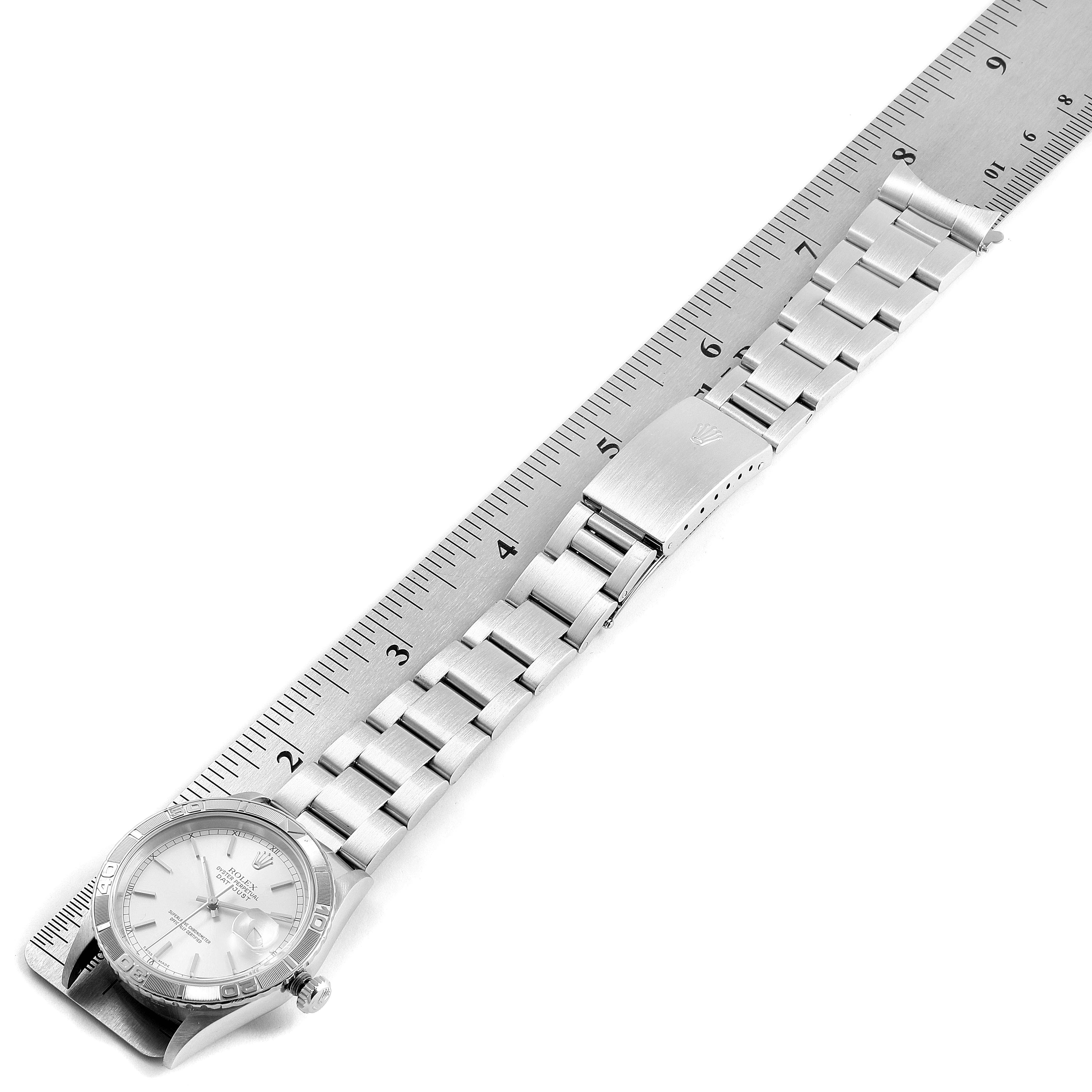 The Rolex Turn-o-Graph 16264 Men's Stainless Steel Silver Dial 16264 Men's Stainless Steel Silver Dial watch is displayed face-up with its band fully extended, measured next to a ruler.