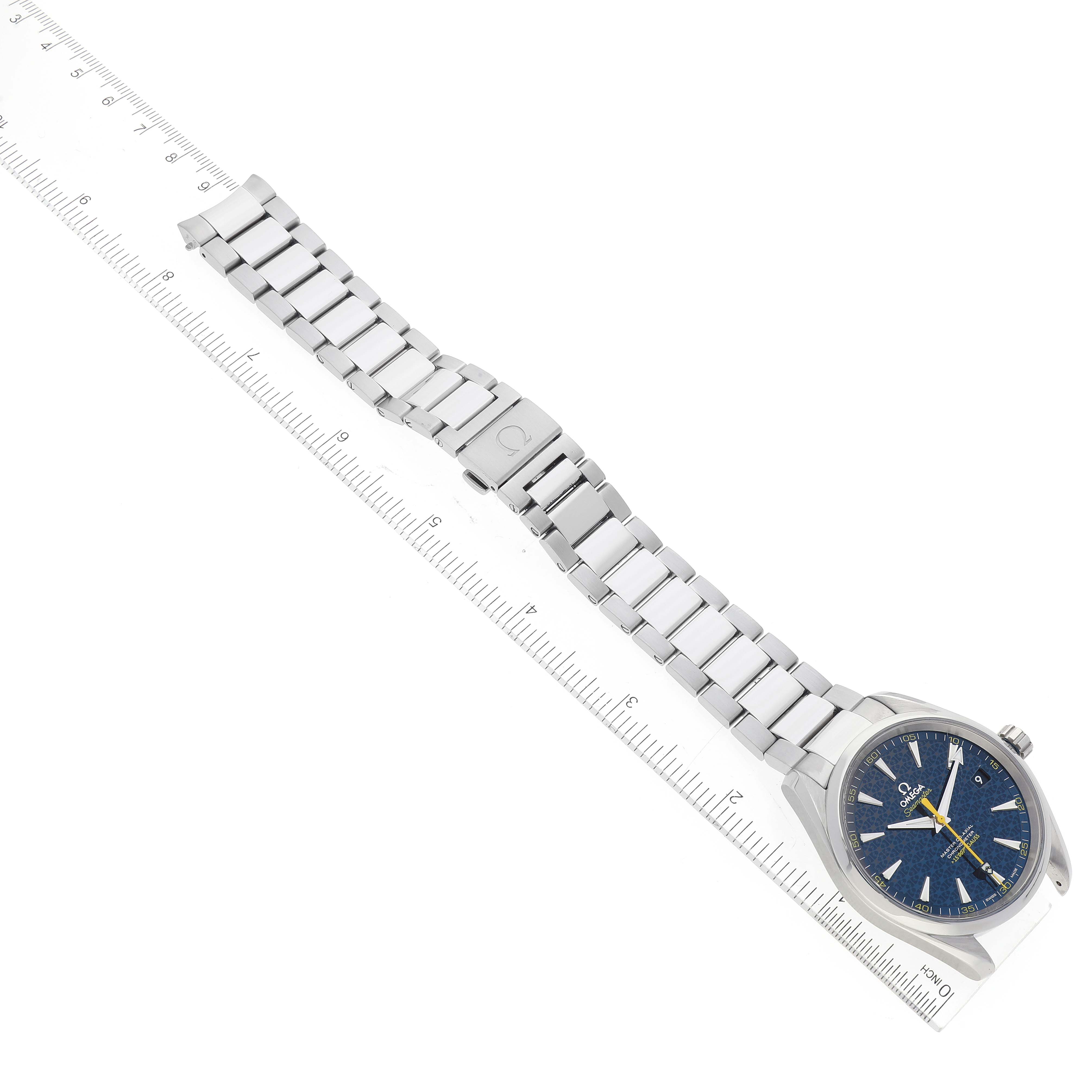 The image shows a side-angle view of an Omega Aqua Terra 231.10.42.21.03.004 Men's Stainless Steel Blue Dial 231.10.42.21.03.004 Men's Stainless Steel Blue Dial watch, displaying the face and metallic bracelet laying alongside a ruler.