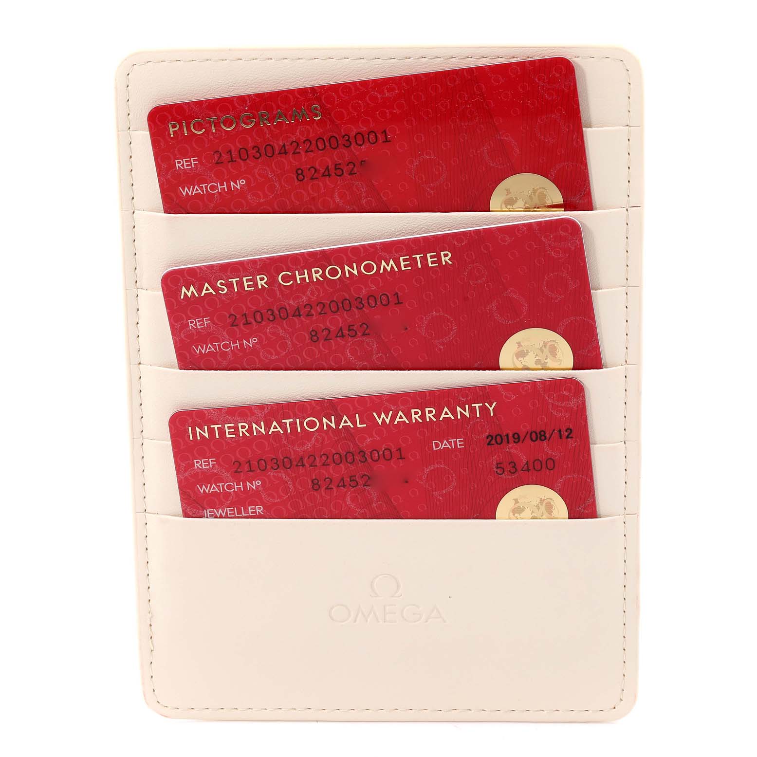 The image shows three red cards (Pictograms, Master Chronometer, and International Warranty) in a white Omega cardholder for a Seamaster model by Omega.