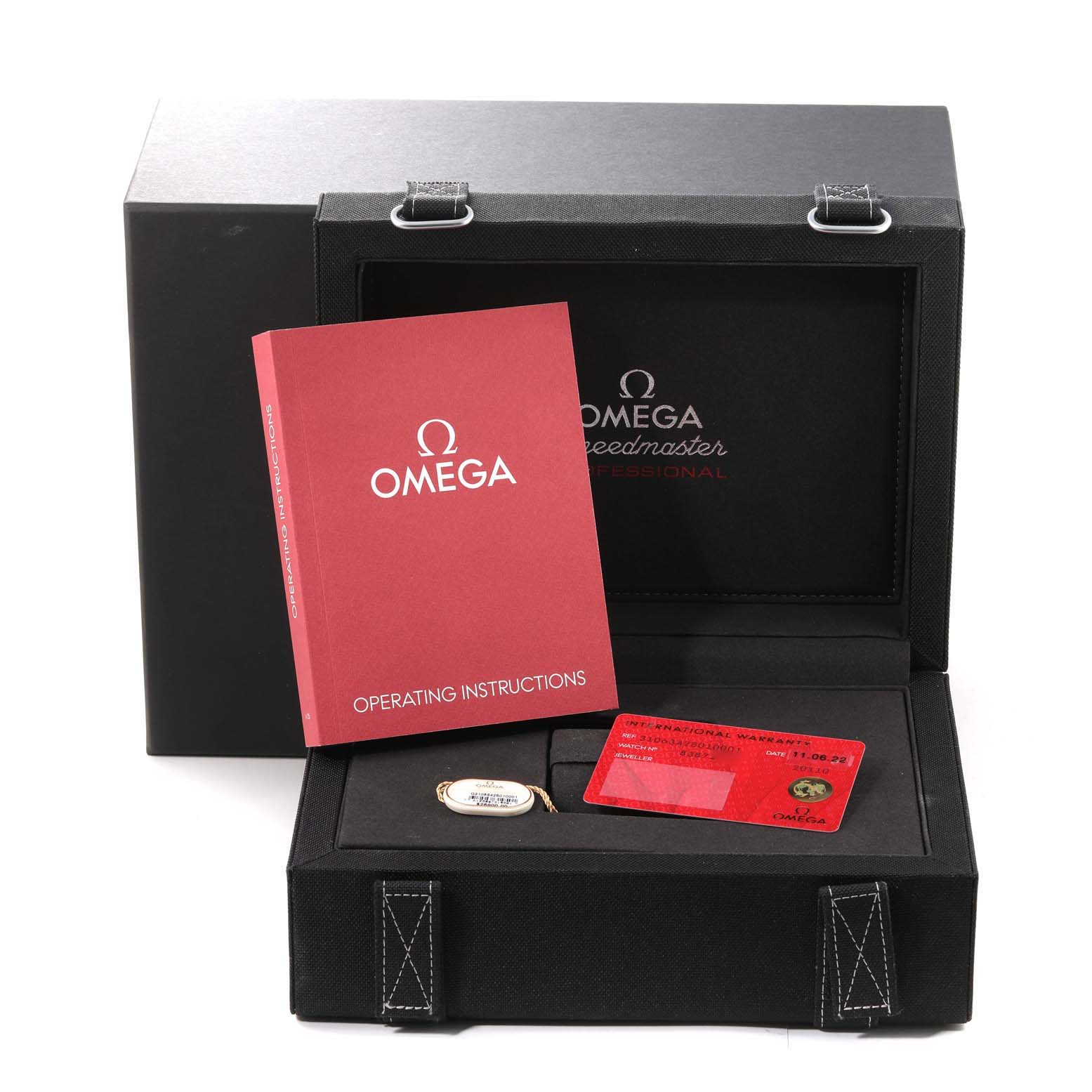 The image shows an Omega Speedmaster 310.63.42.50.10.001 Men's Yellow Gold Green Dial 310.63.42.50.10.001 Men's Yellow Gold Green Dial packaging, including the instruction manual, warranty card, and medallion, displayed from a front angle.