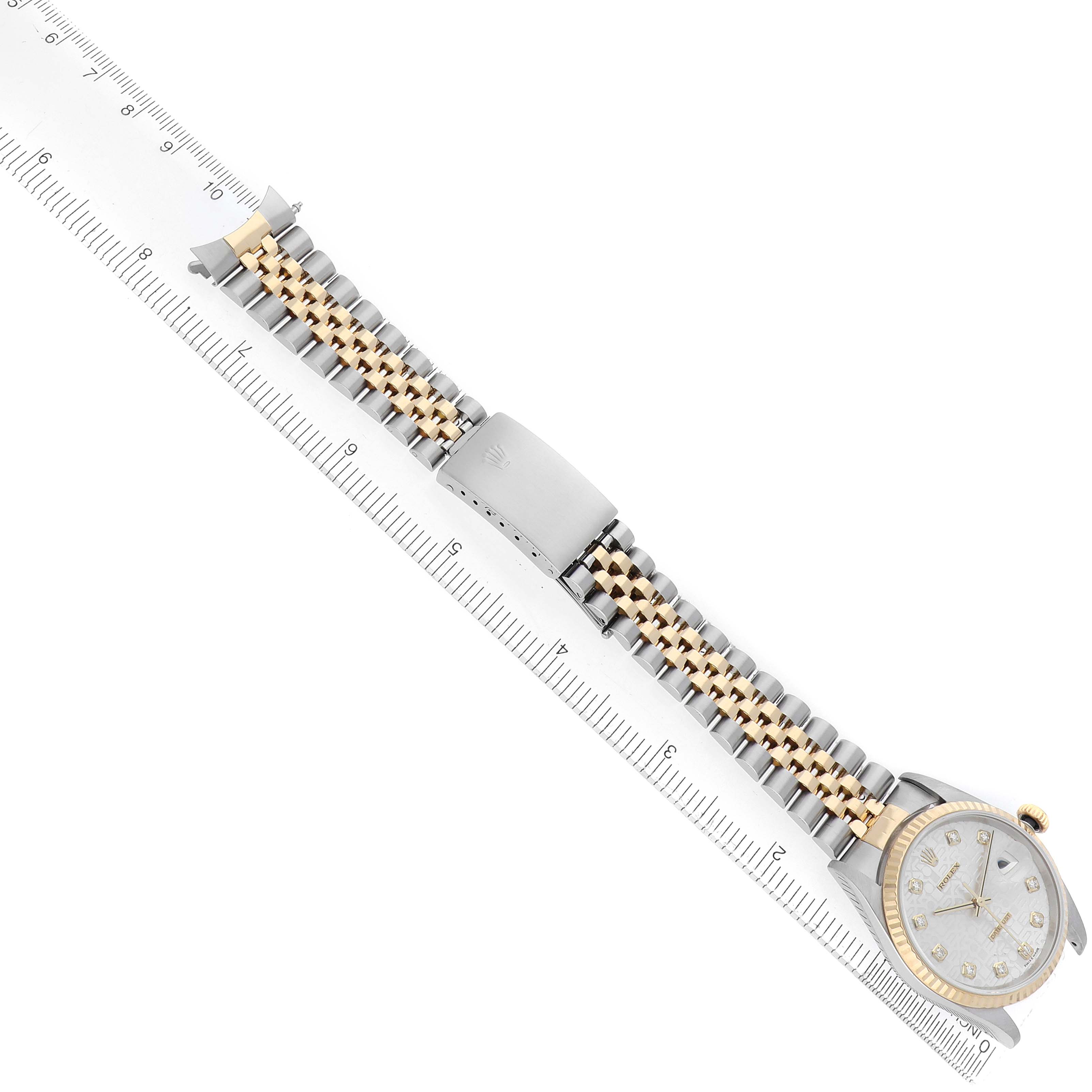 The Rolex Datejust 16233 Men
s Steel and Gold (two tone) Silver Dial watch is shown from a top-down angle, displaying the face, bracelet, and clasp fully extended alongside a ruler.