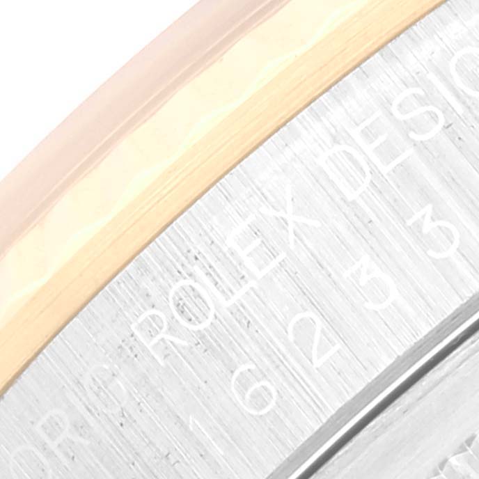 The image shows a close-up of the side of the Rolex Datejust 16233 Men's Steel and Gold (two tone) White Dial 16233 Men's Steel and Gold (two tone) White Dial watch, displaying part of the bezel and engraved text.