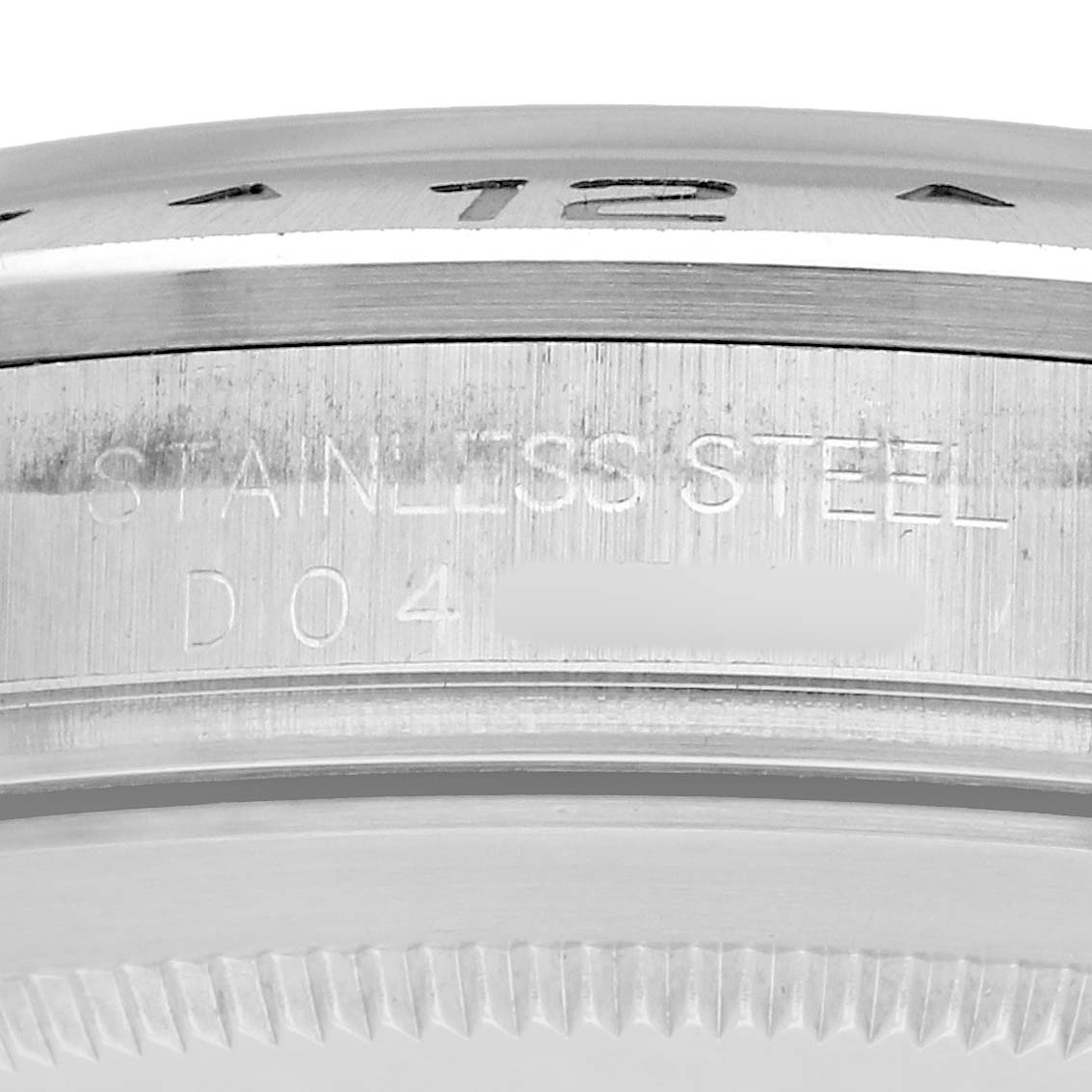 The image shows a close-up of the side of the Rolex Explorer 16570 Men
s Stainless Steel Black Dial
s bezel, highlighting the "Stainless Steel" engraving.