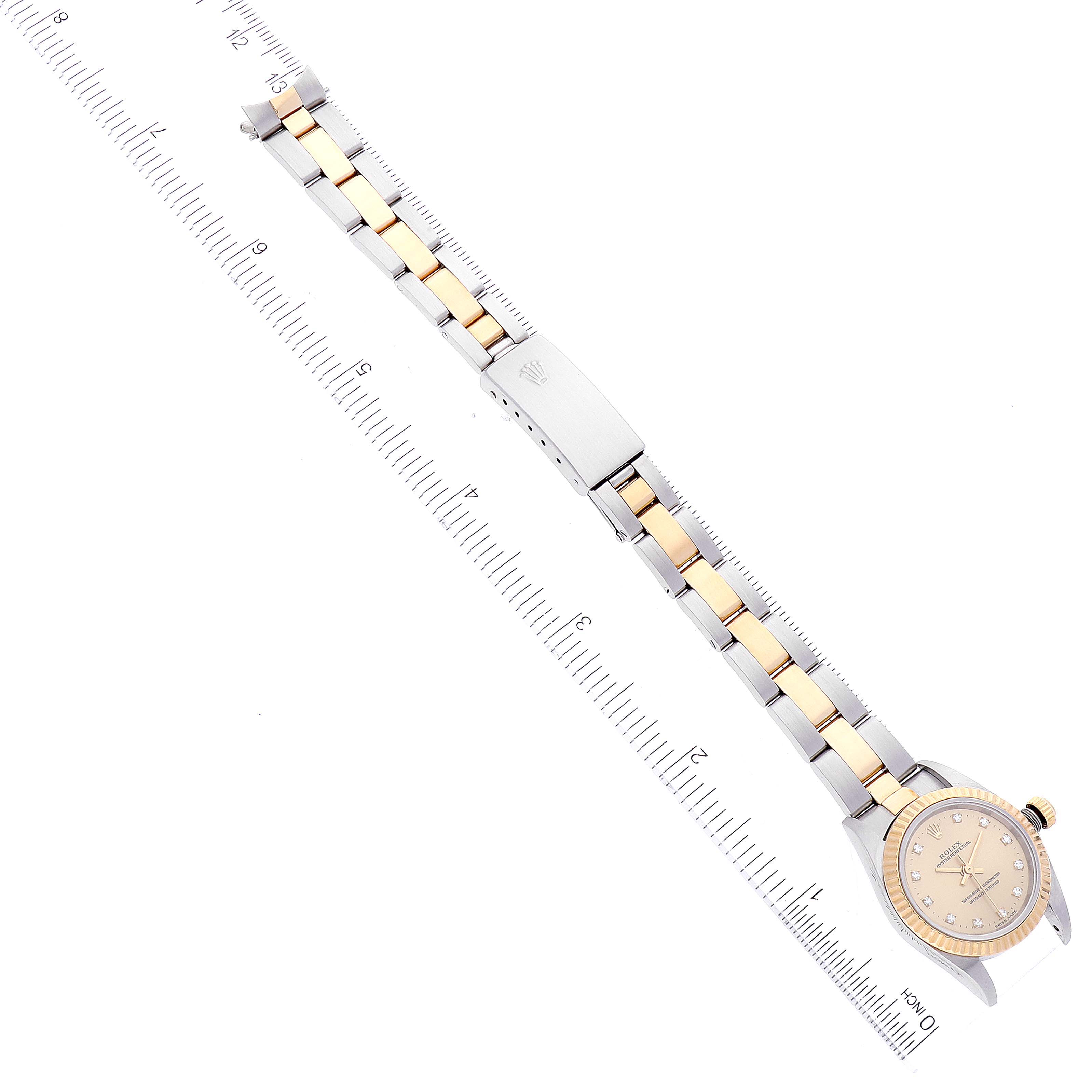 The image shows a Rolex Oyster Perpetual 76193 Women's Steel and Gold (two tone) Champagne Dial 76193 Women's Steel and Gold (two tone) Champagne Dial watch with a two-tone bracelet, viewed from above with a measuring ruler for scale.