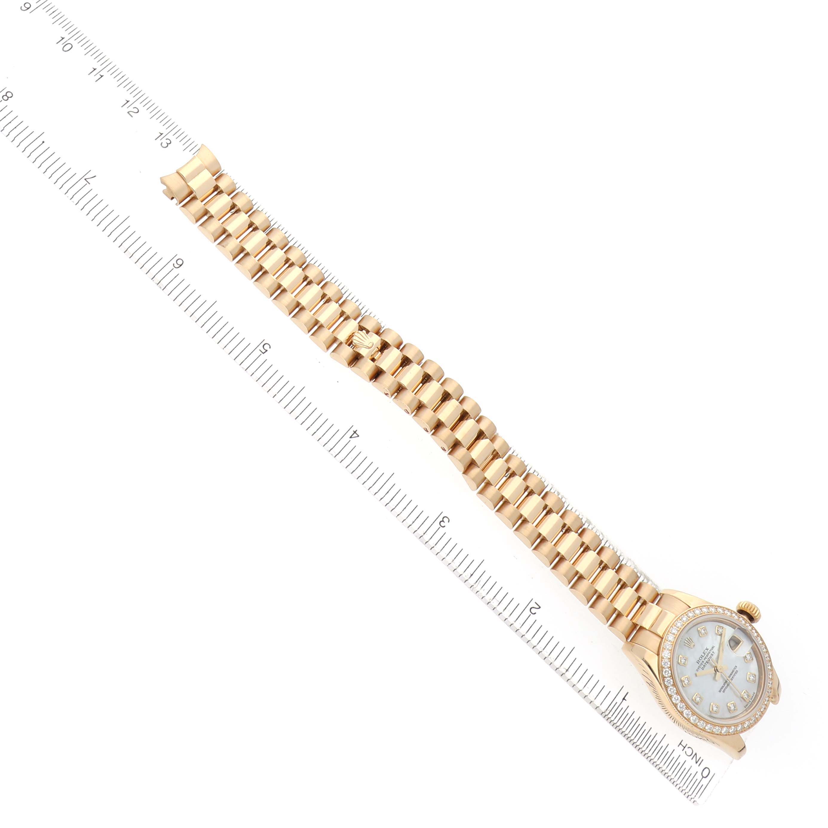 The Rolex President 179138 Women
s Yellow Gold Mother of Pearl Dial watch is shown from a top view, displaying the face, bezel, and the full length of the bracelet alongside a ruler.