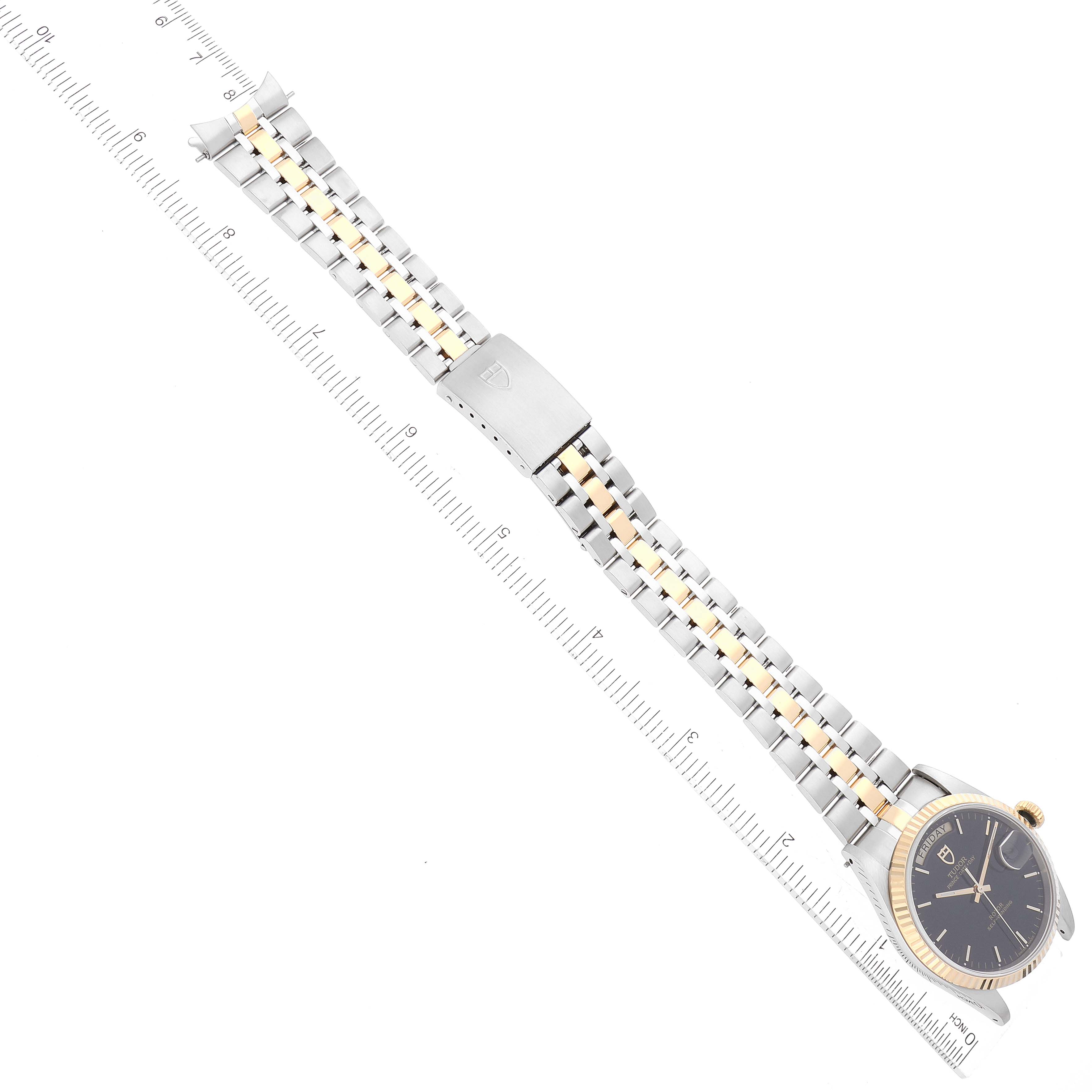The image shows a Tudor Prince 76213 Men's Steel and Gold (two tone) Black Dial 76213 Men's Steel and Gold (two tone) Black Dial model watch laid flat, highlighting the watch face, bracelet, and clasp alongside a ruler for scale.
