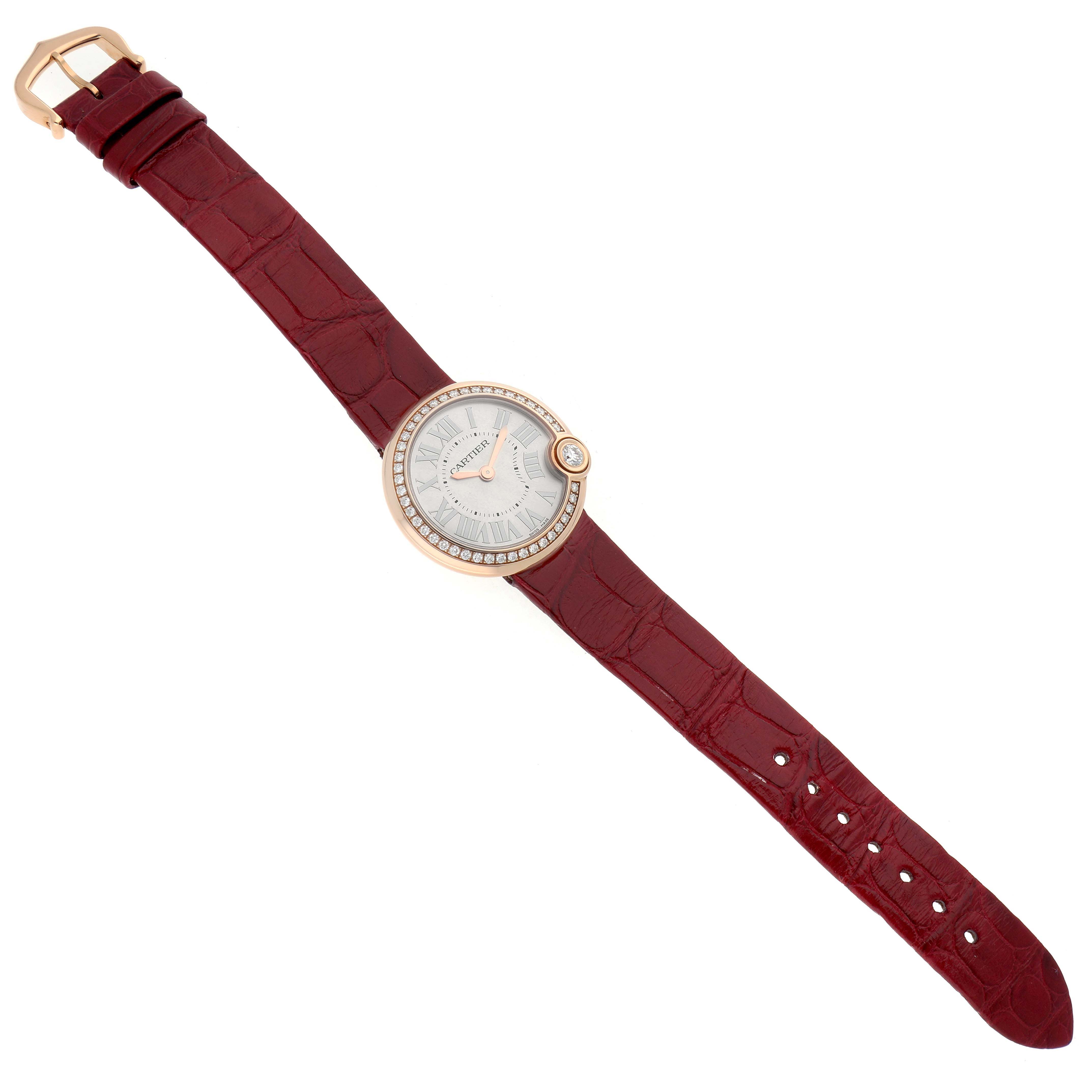 The Cartier Ballon Blanc WJBL0005 Women's Rose Gold Silver Dial watch is shown from a top-down angle, displaying its round face, diamond-set bezel, and red strap.
