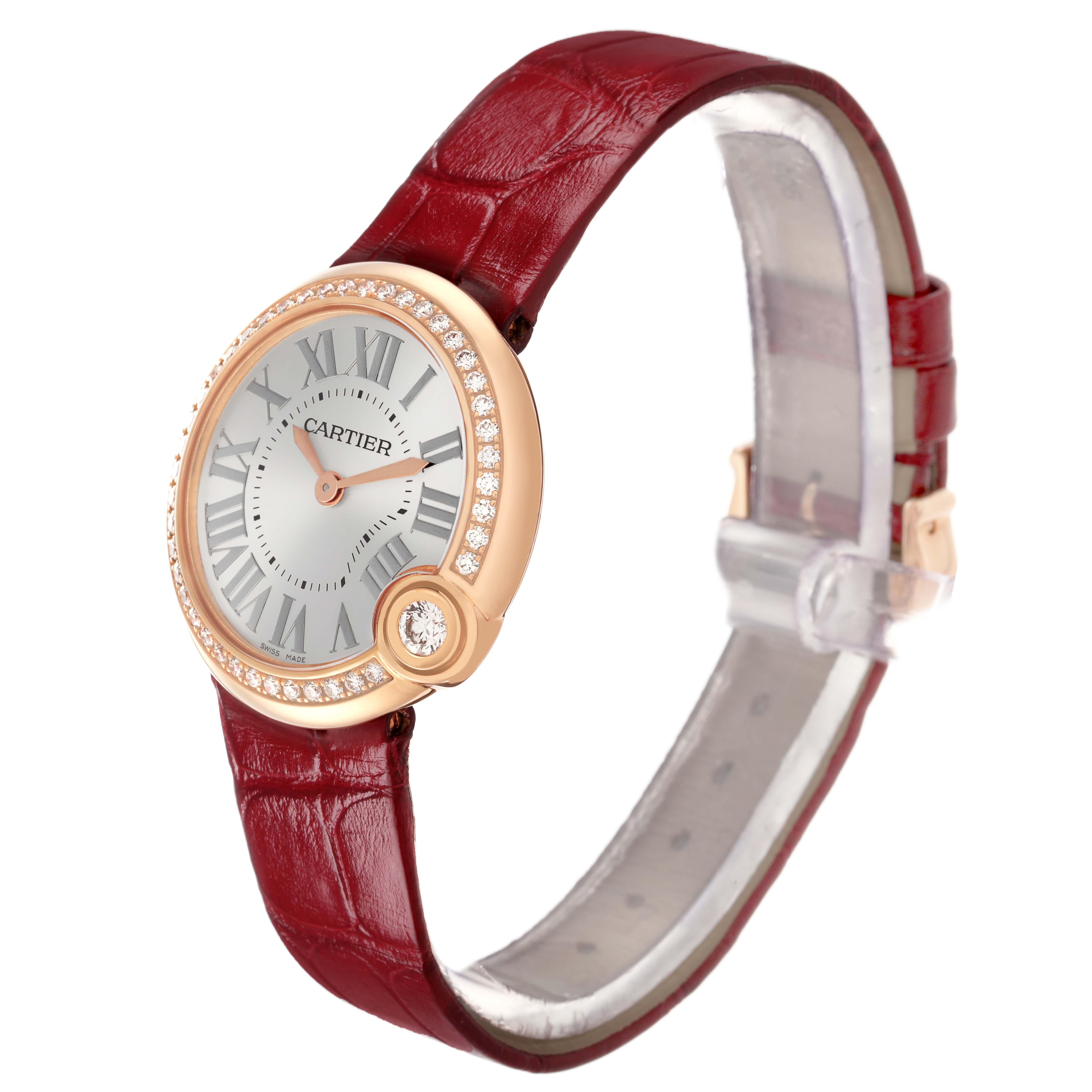 The Cartier Ballon Blanc WJBL0005 Women's Rose Gold Silver Dial watch is shown at an angled side view, highlighting its face, diamond bezel, and red leather strap.