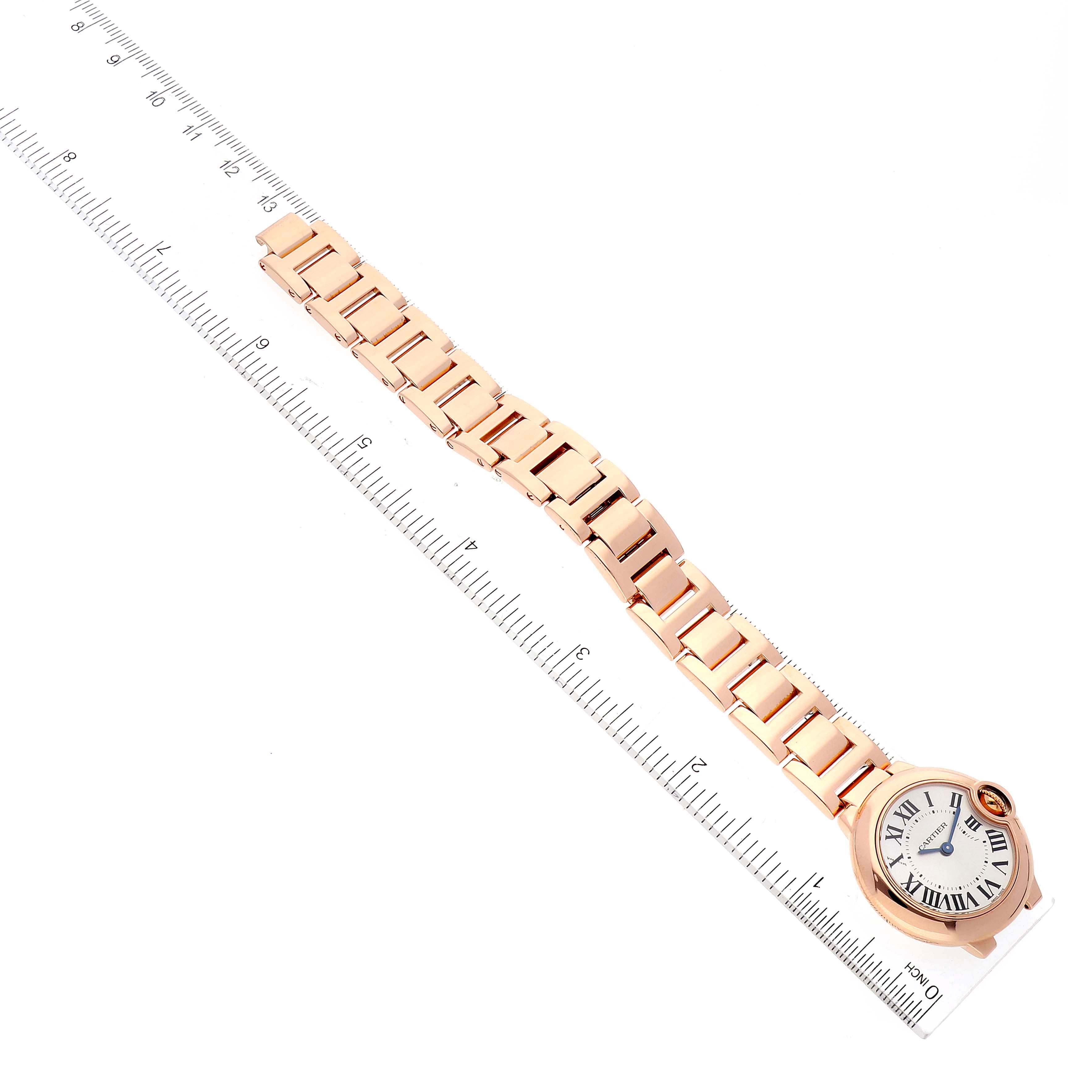 The image shows an overhead view of a Cartier Ballon Bleu W69002Z2 Women's Rose Gold Silver Dial W69002Z2 Women's Rose Gold Silver Dial watch with its face and bracelet laid next to a ruler.