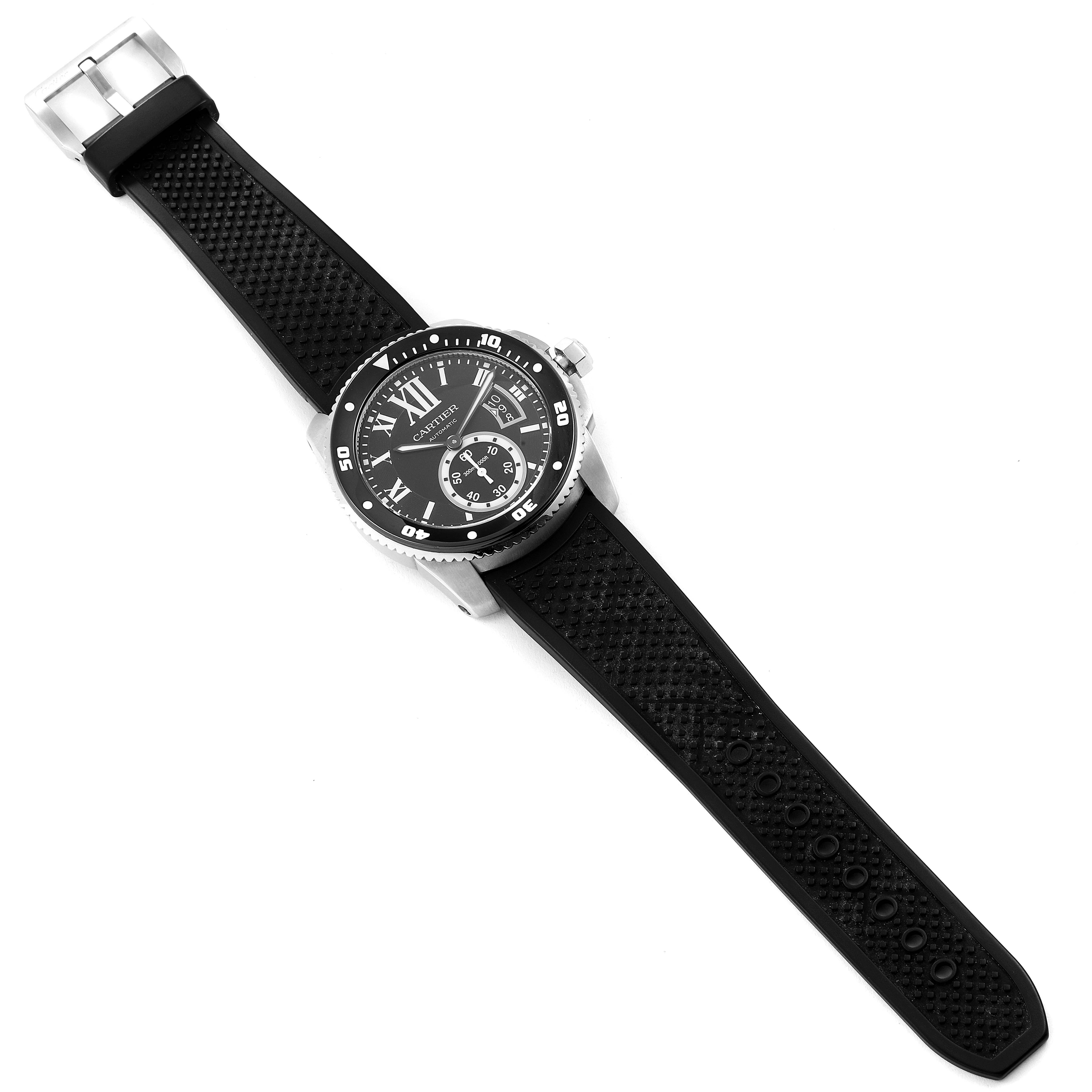 The Calibre de Cartier watch by Cartier is shown from a top-down angle, displaying its black textured strap and round black dial.