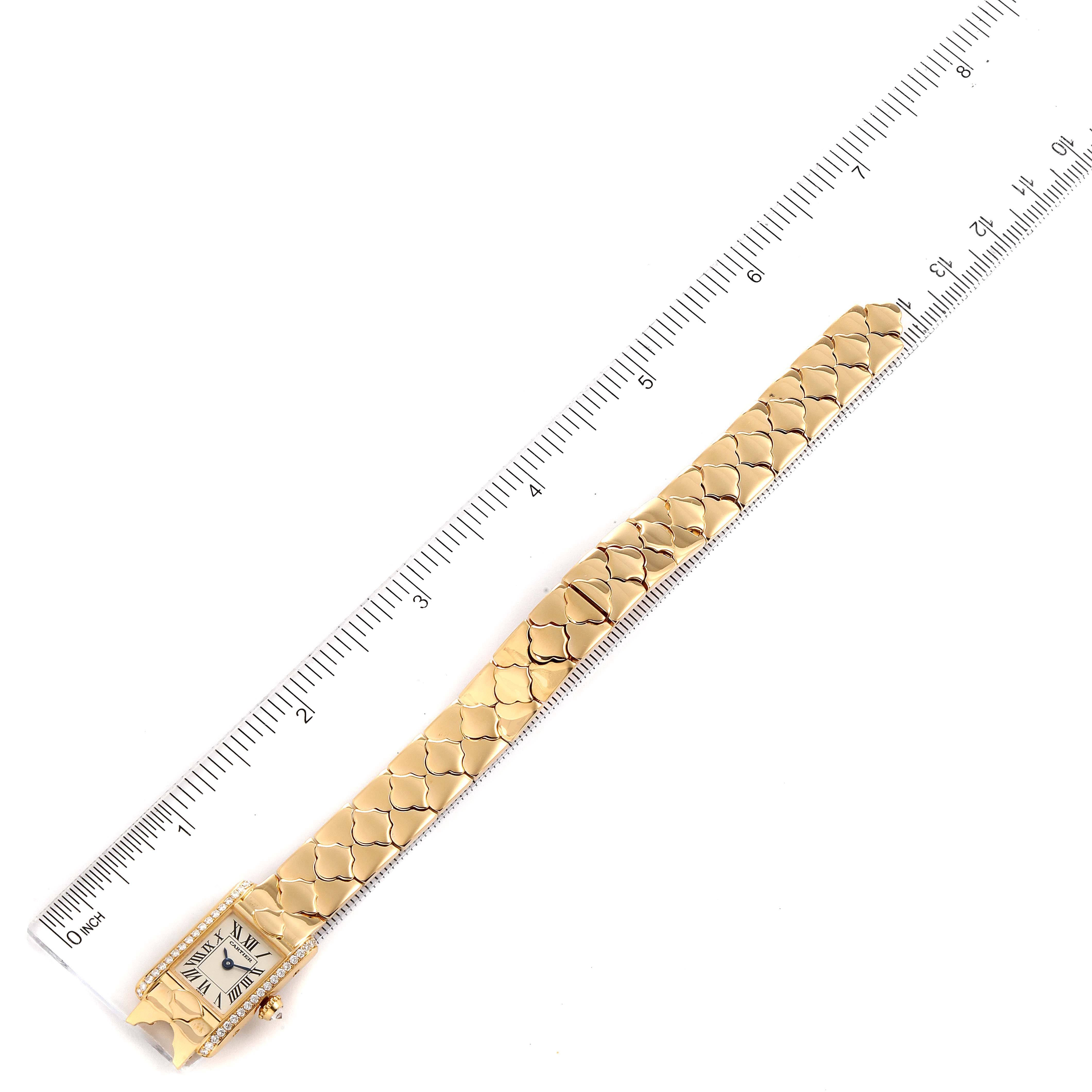 The Cartier Tank Classic 1361 Women's Yellow Gold Silver Dial 1361 Women's Yellow Gold Silver Dial watch is shown from a top-down angle, displaying its gold bracelet and square face alongside a ruler for scale.