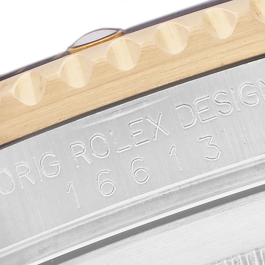 The image shows a close-up of the Rolex Submariner 16613 Men
s Steel and Gold (two tone) Champagne Dial
s engraved case back, highlighting the model number and part of the bezel.